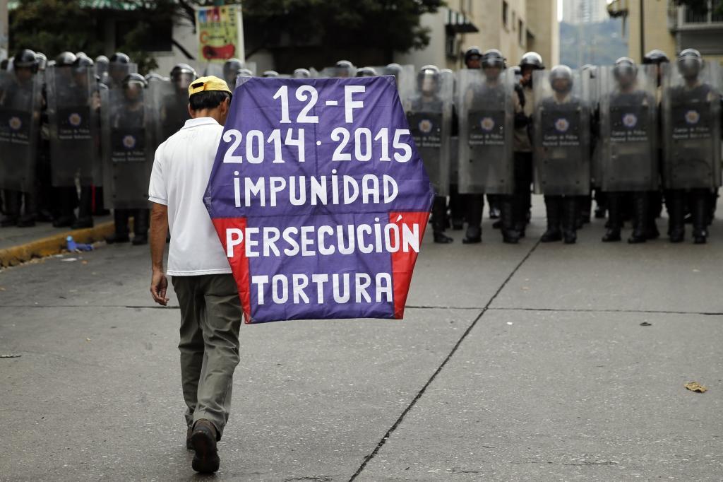 Un hombre anda con un cartel frente a la policía... | Internacional ...