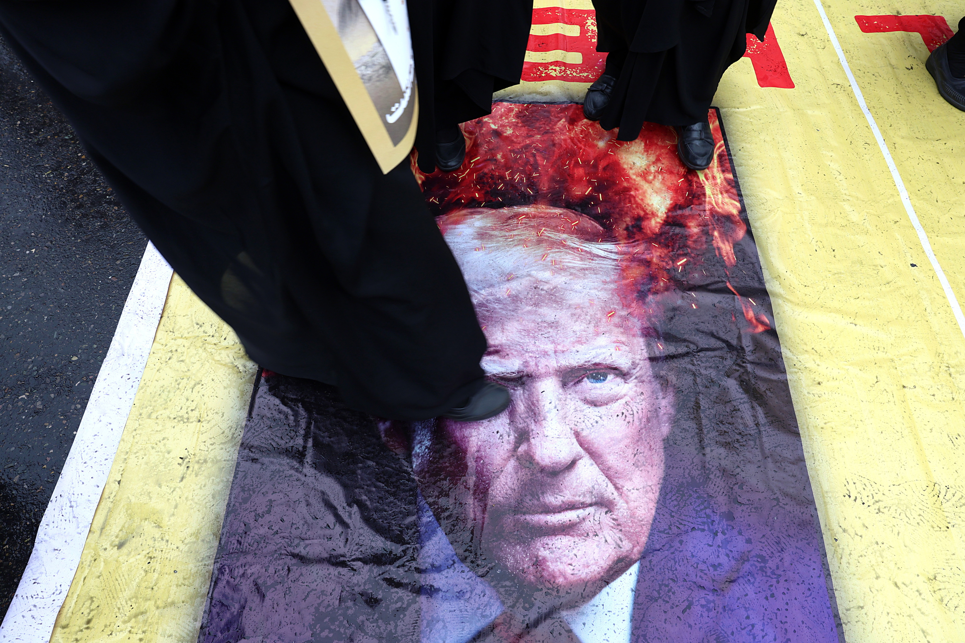 Los manifestantes pisotean  un cartel que muestra al presidente estadounidense, Donald Trump.