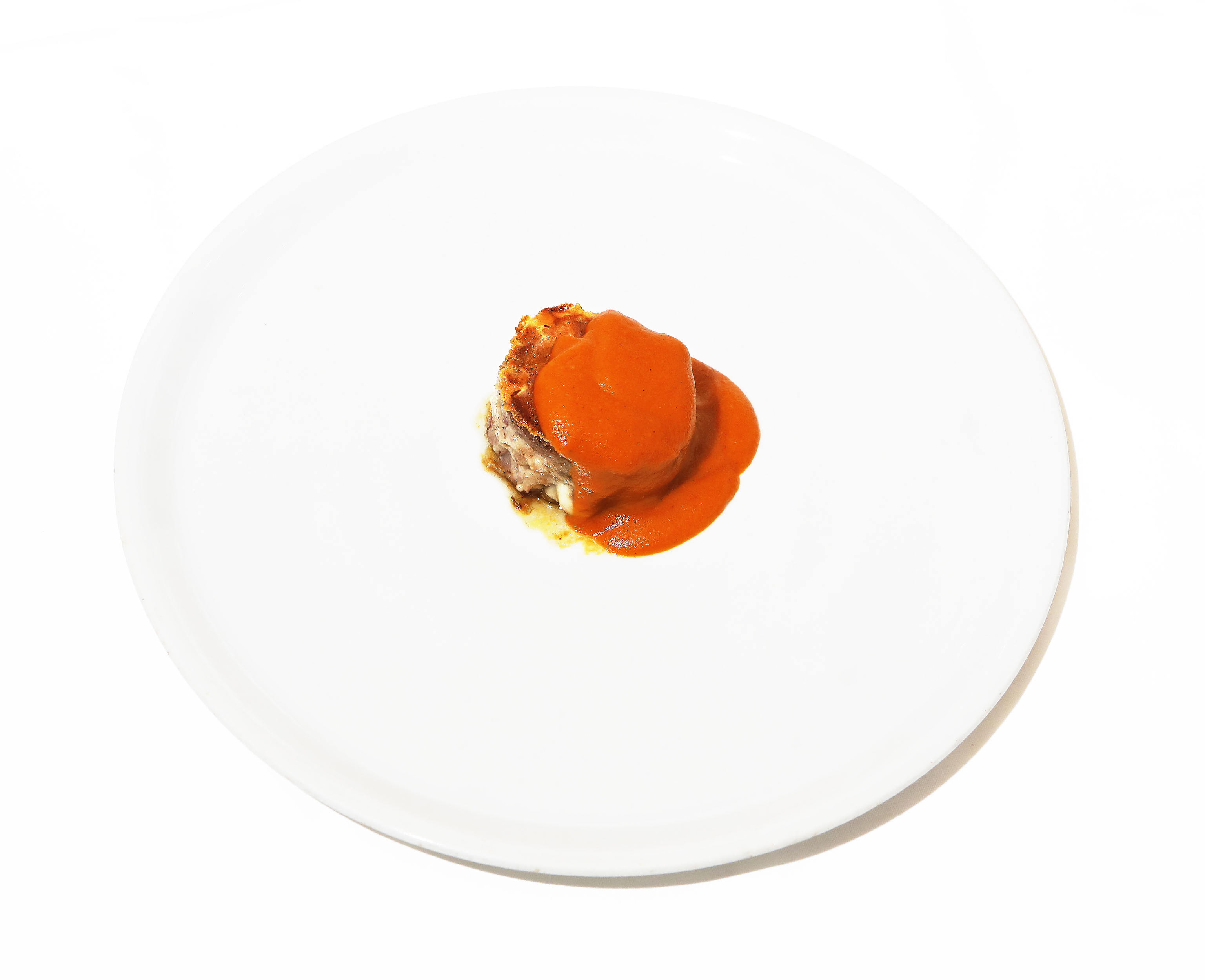 Rulo de manita, morrete y oreja de cochinillo con salsa brava.
