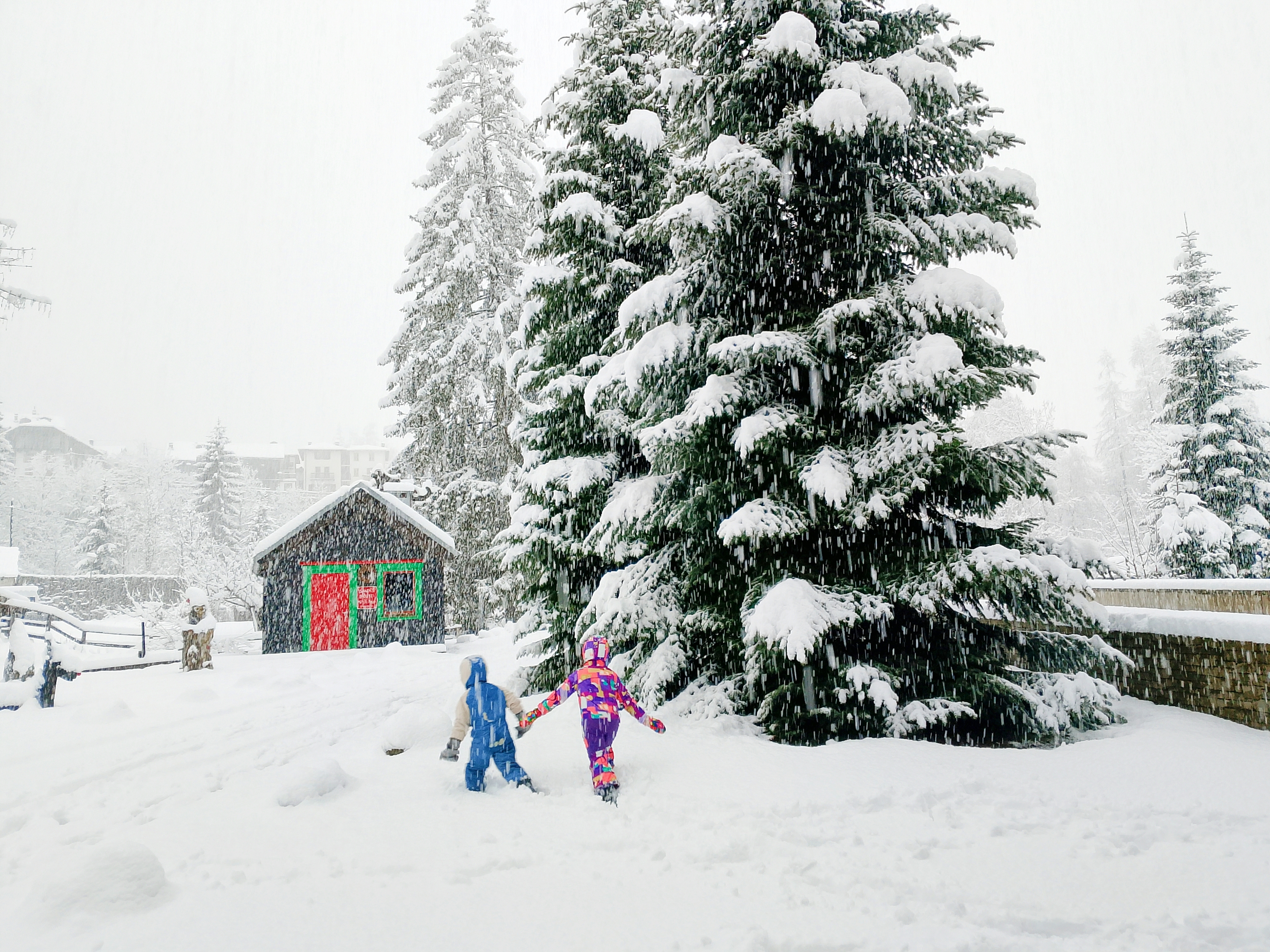 Dos niños jugando junto a la casa de Papá Noel del jardín.