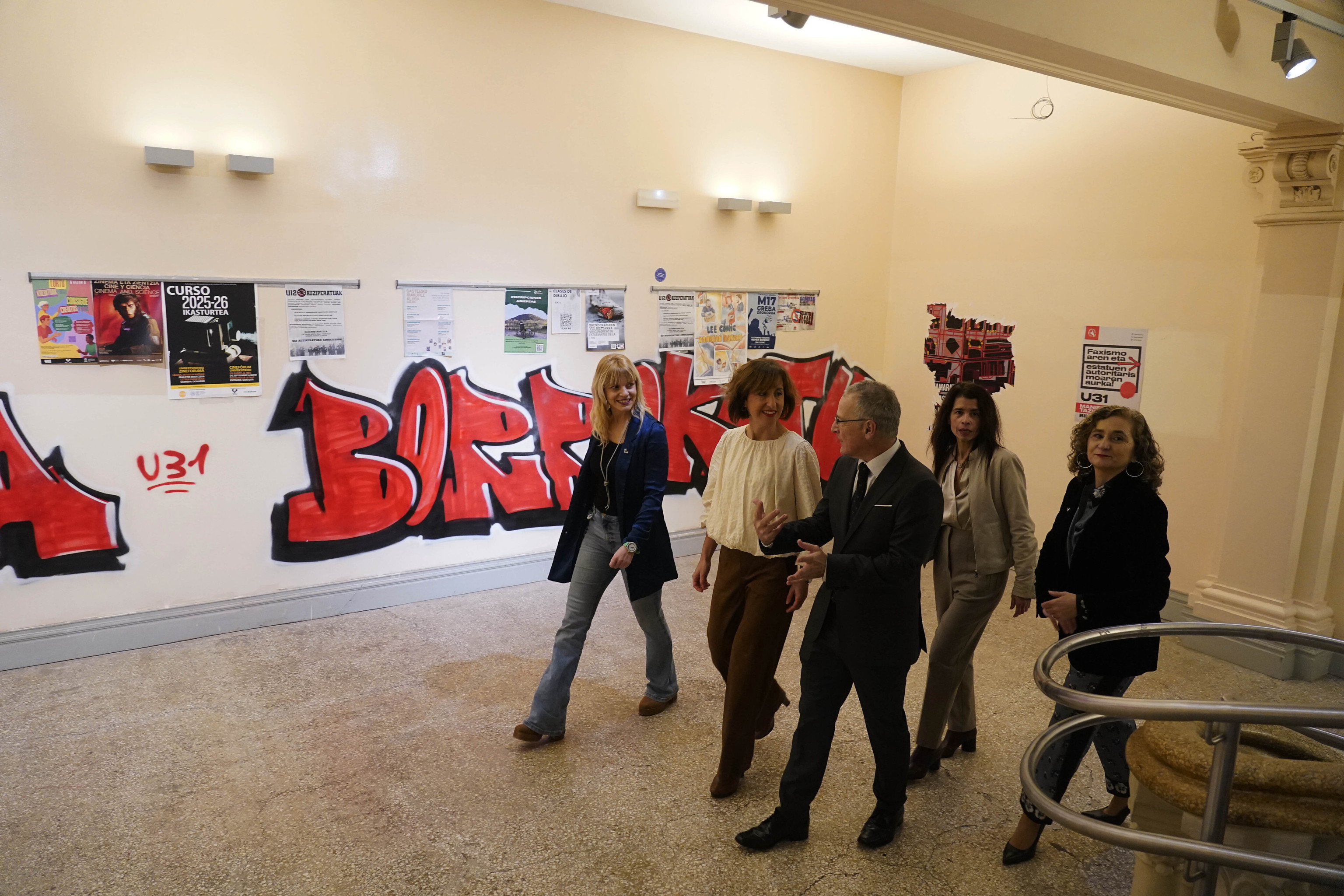 El rector Bengoetxea junto a parte de su equipo camina junto a uno de los murales radicales pintados en el interior del Aulario de Las Nieves en Vitoria.