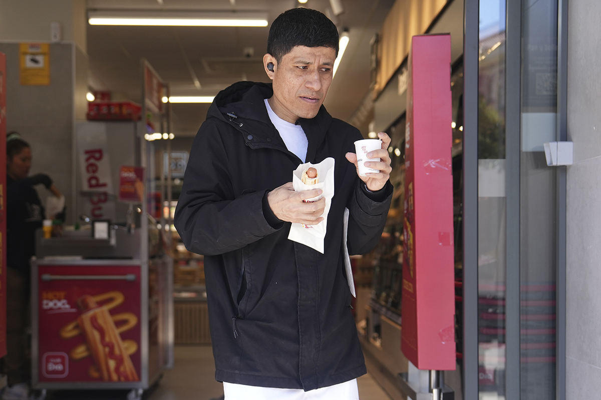 Un cliente sale de Dia con un perrito caliente y un café