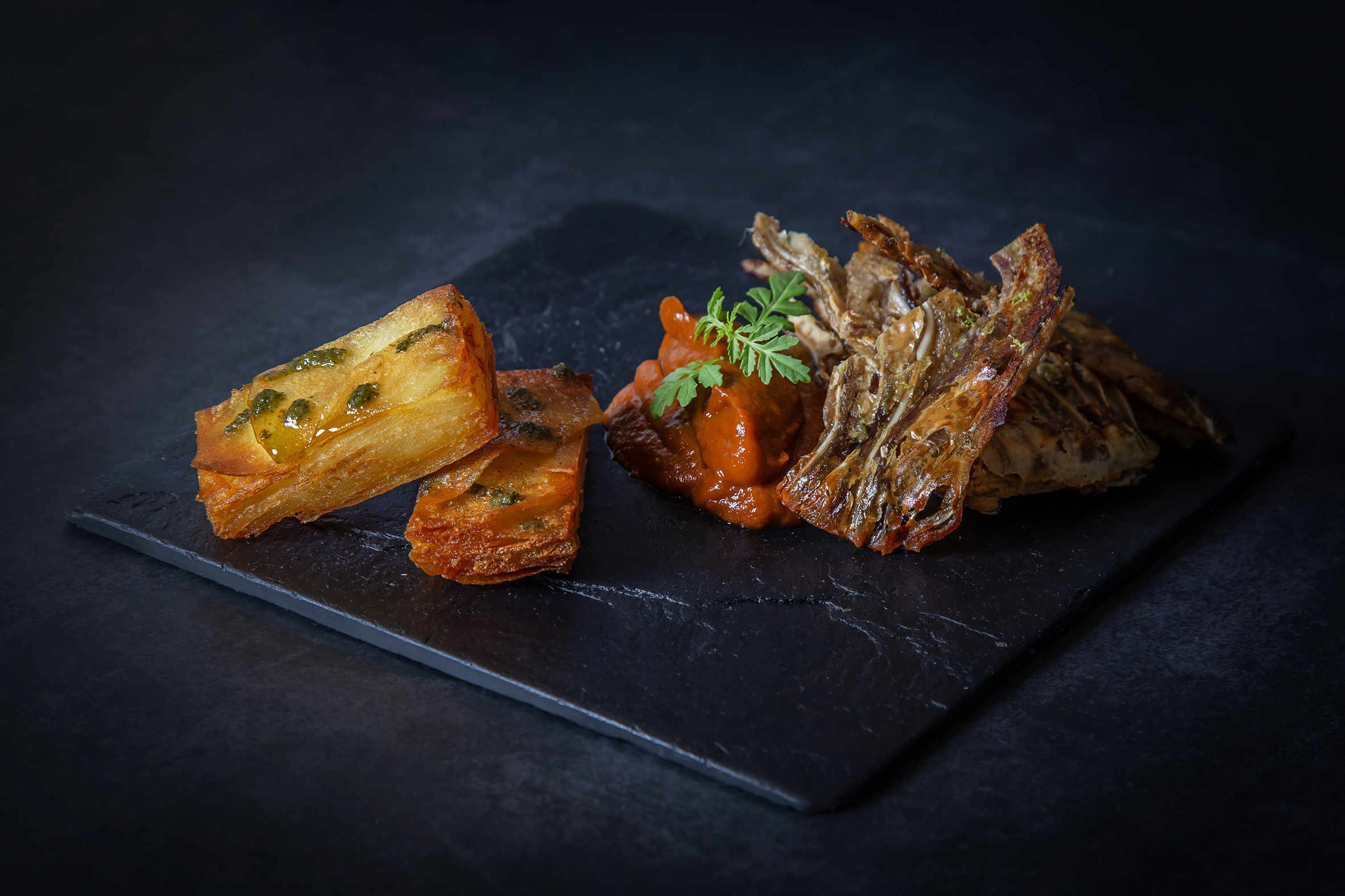 'Los Minutejos de Cokima': chips de oreja de cerdo crujiente con milhojas de patata y salsa brava.