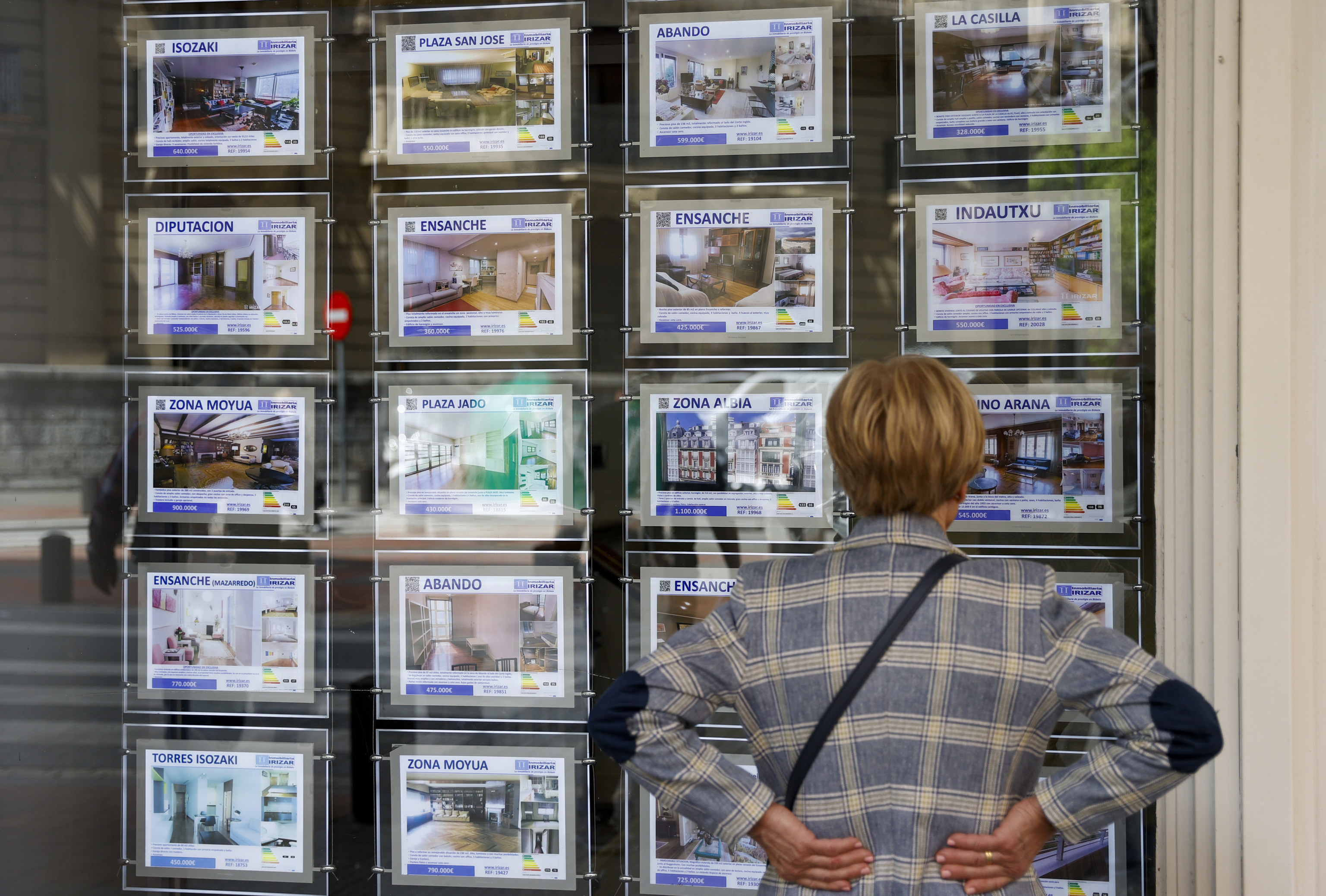 Una mujer mira la oferta de viviendas en una inmobiliaria.