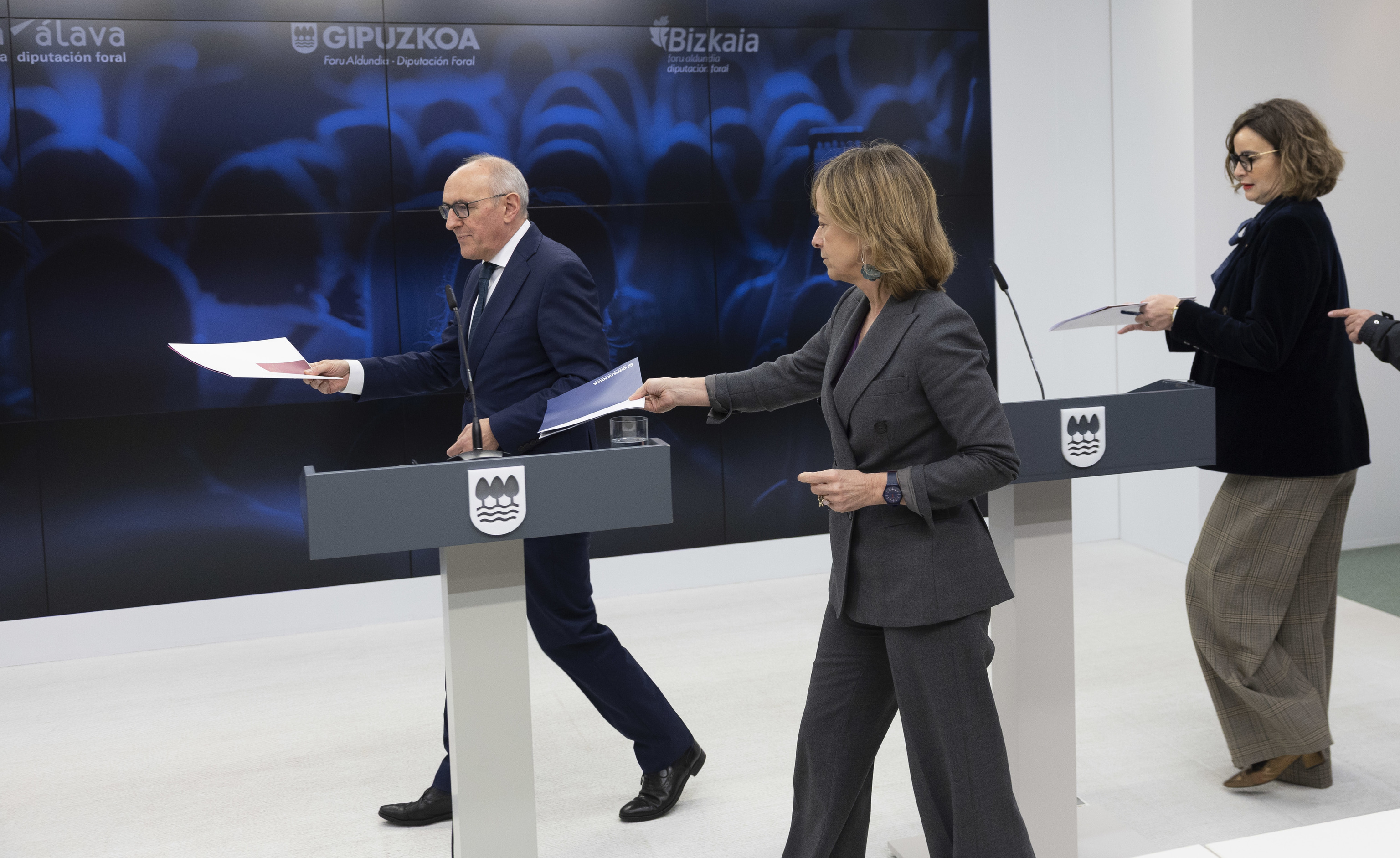 Ramiro González, Eider Mendoza y Elixabete Etxanobe se dirigen a sus estrados con el logo de Gipuzkoa antes de explicar la batería de medidas fiscales.