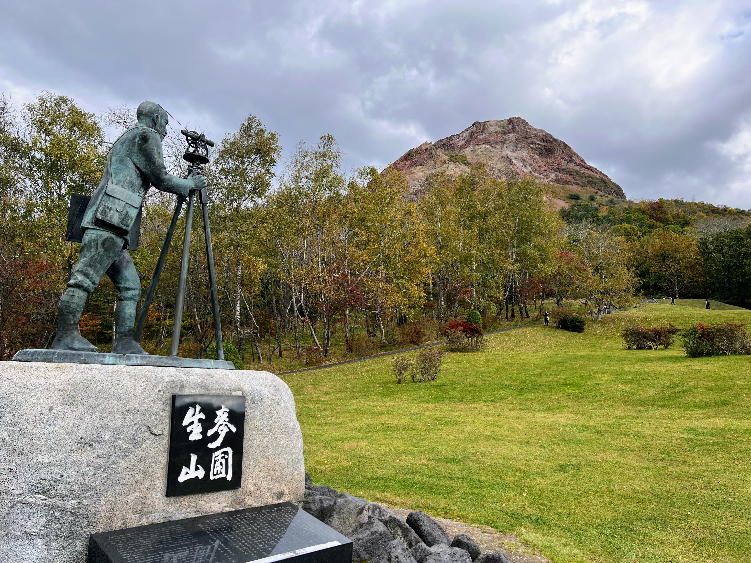 Estatua dedicada al cartero Masao Mimatsu y, en frente, el volcán Showa Shinzan.