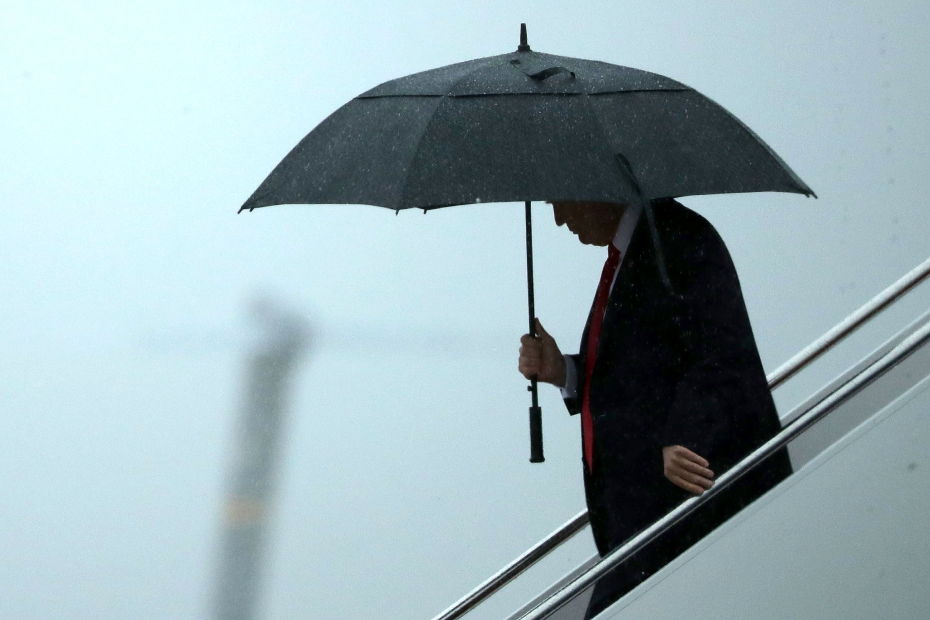 Donald Trump desciende del 'Air Force One' protegido por un paraguas.
