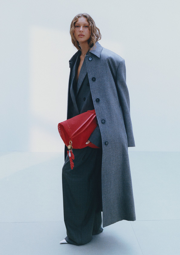 Abrigo oversized (299 euros) y chaqueta de doble botonadura (279 euros), ambas elaboradas en viscosa Ecojilin, fabricada a partir de residuos de algodón, ylana RWS, que certifica el bienestar animal. Bolso rojo de malla realizado en poliéster reciclado (99 euros).