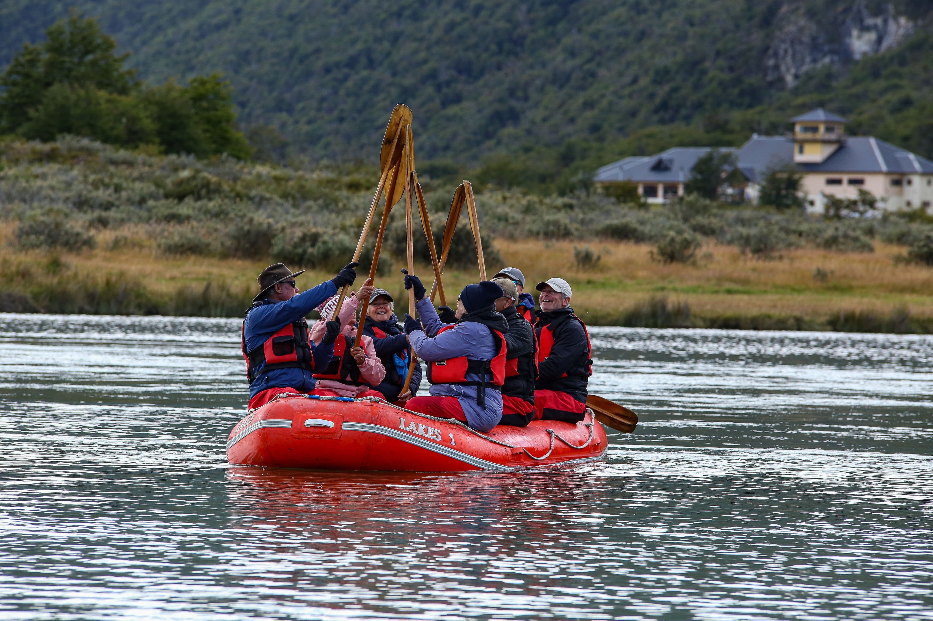 Turistas haciendo kayak con los remos en alto.