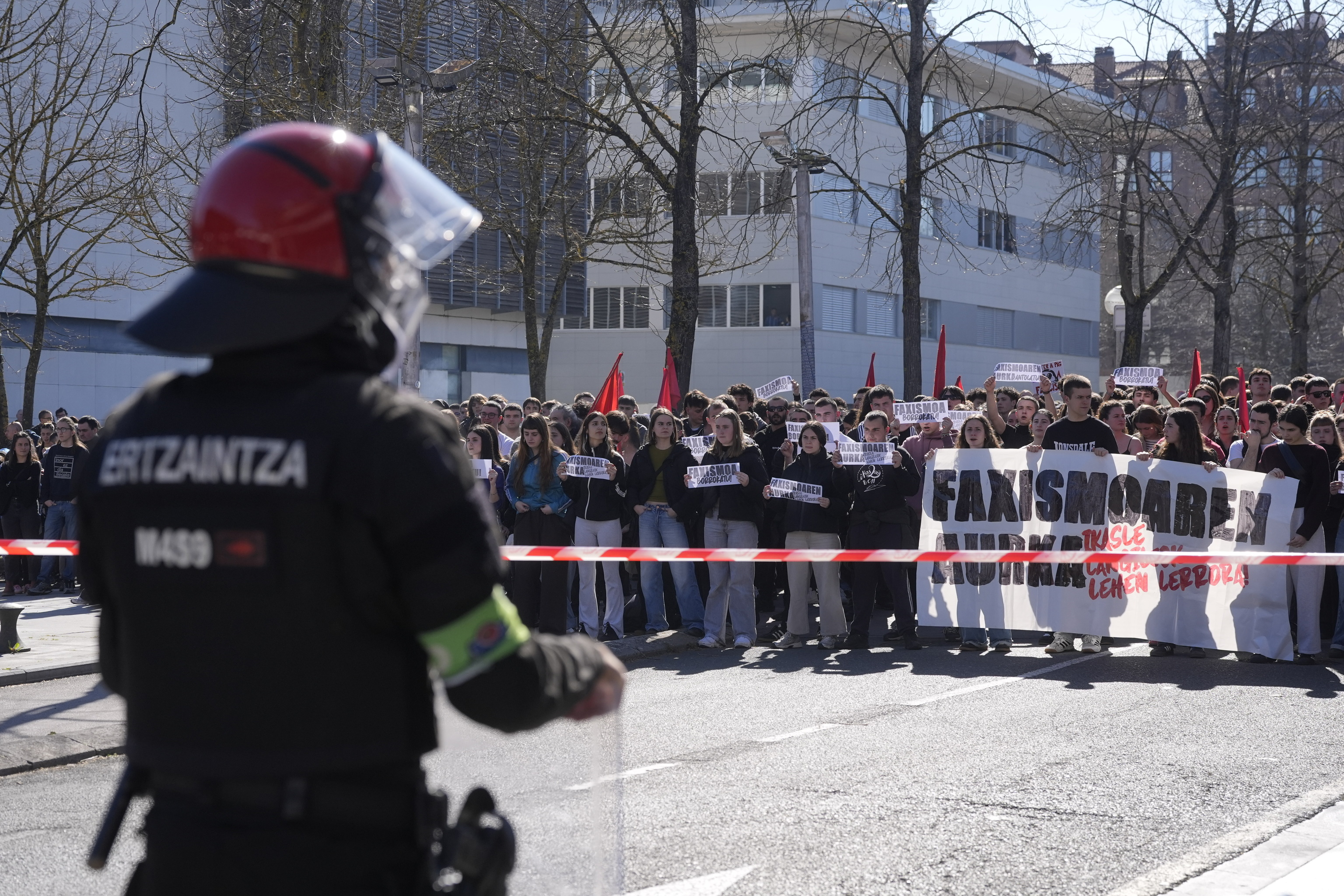 Un ertzaina participa en el dispositivo de seguridad desplegado para impedir que militantes de grupos radicales concentrados contra un acto de Vox en el campus universitario de Vitoria.