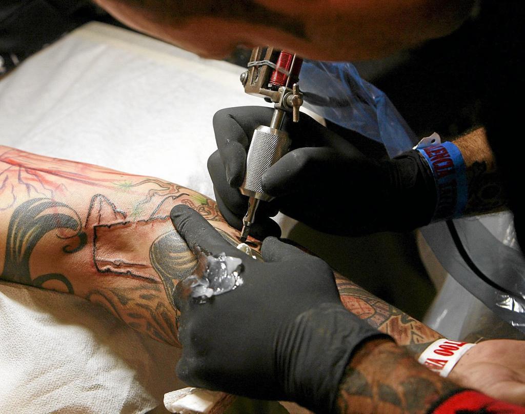 Un tatuador aplicando su t�cnica en un brazo.