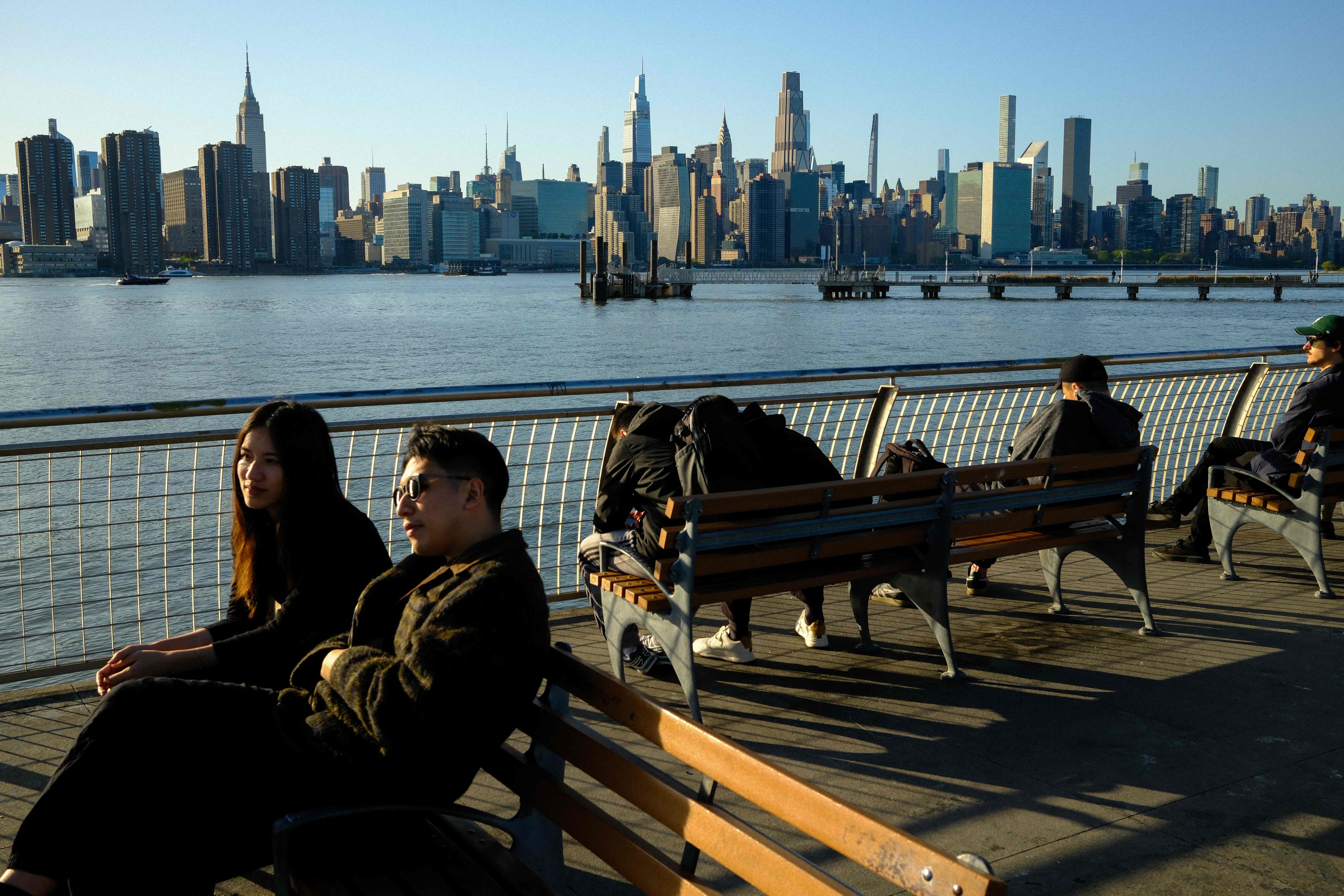 Gente sentada junto al East River con el skyline de Manhattan.