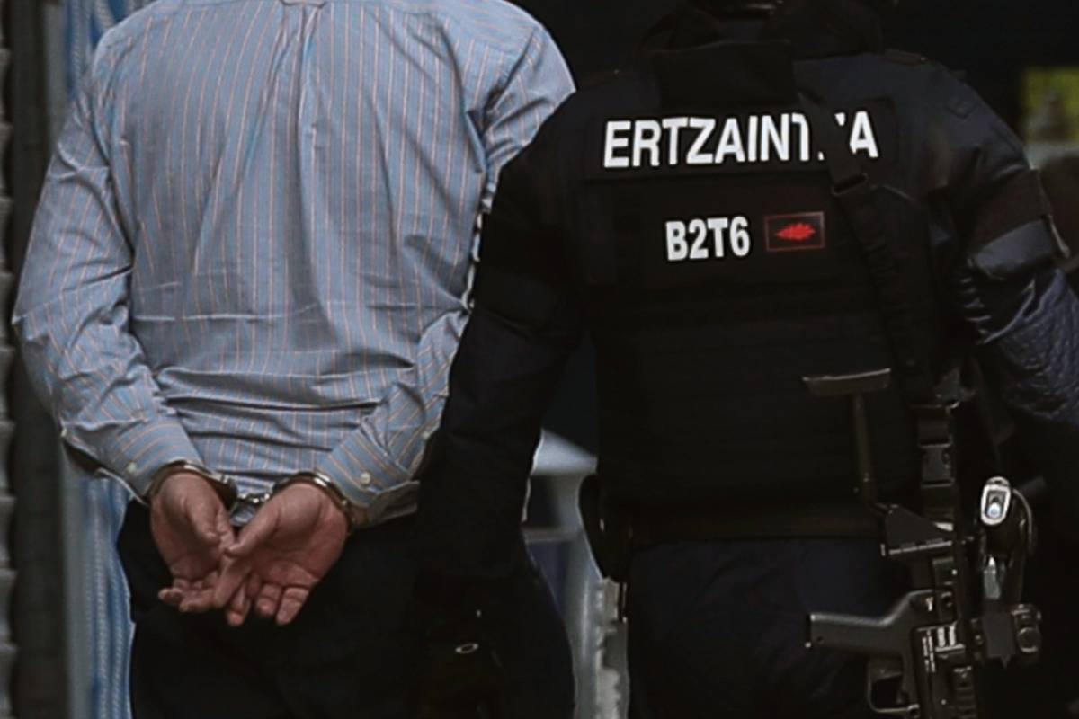 Un ertzaintza con un hombre detenido.