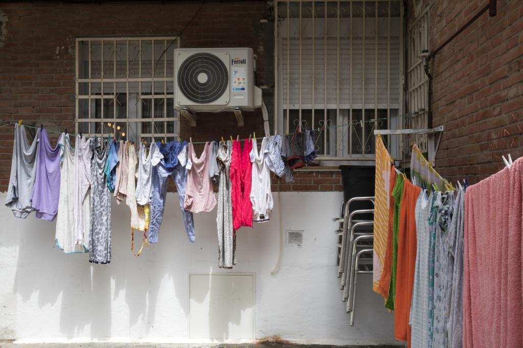 Ropa tendida en la calle junto a un aire acondicionado.