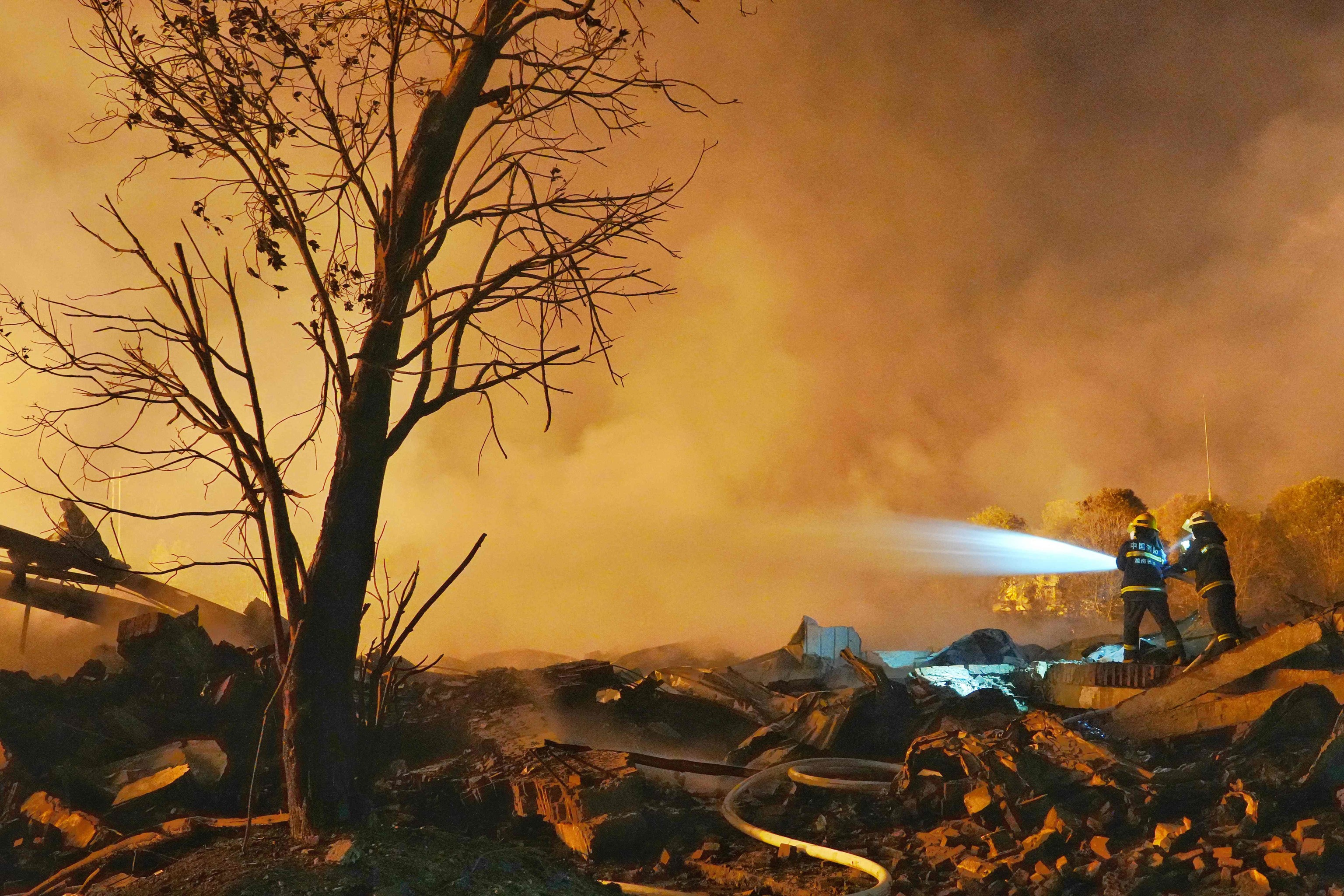 Dos bomberos echan agua en el lugar de la explosi�n de una f�brica de fuegos artificiales en Liuyang, en la provincia china de Hunan.