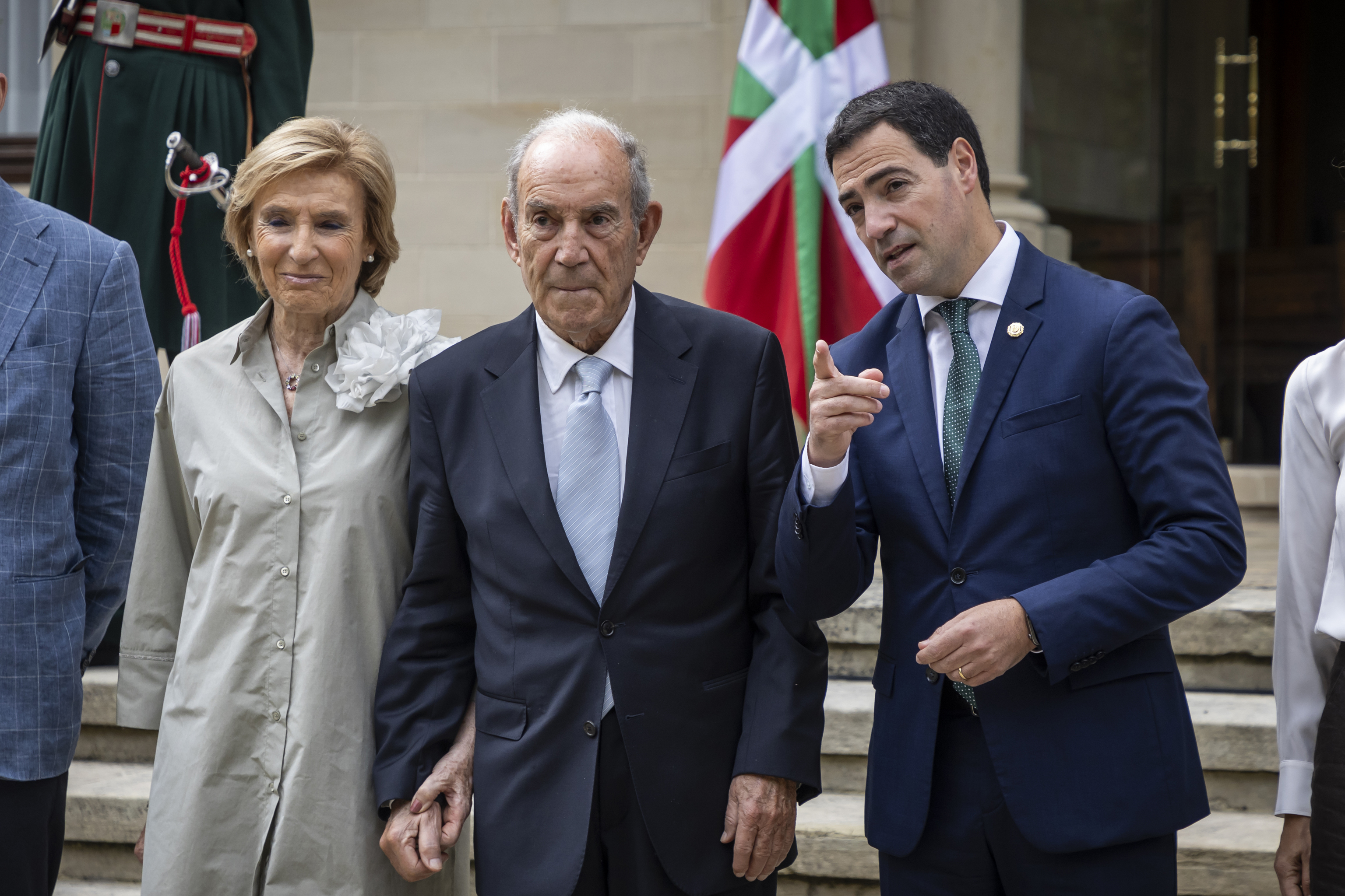 El lehendakari Pradales le indica a Carlos Garaikoetxea y a su mujer Sagrario Mina un detalle en el jardín del palacio de Ajuria Enea en el homenaje organizado en junio de 2025.