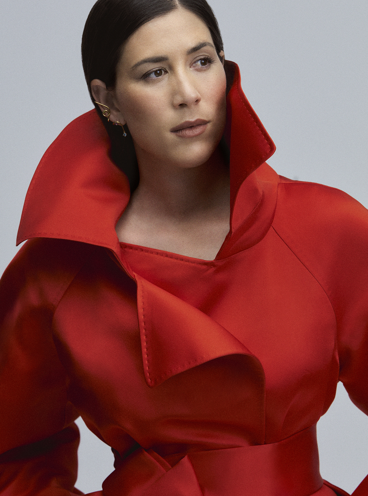 Abrigo largo sat�n rojo de Givenchy y 'earcuff' espiral Lio con ba�o de oro 18 kt sobre plata y gemas de Tous.