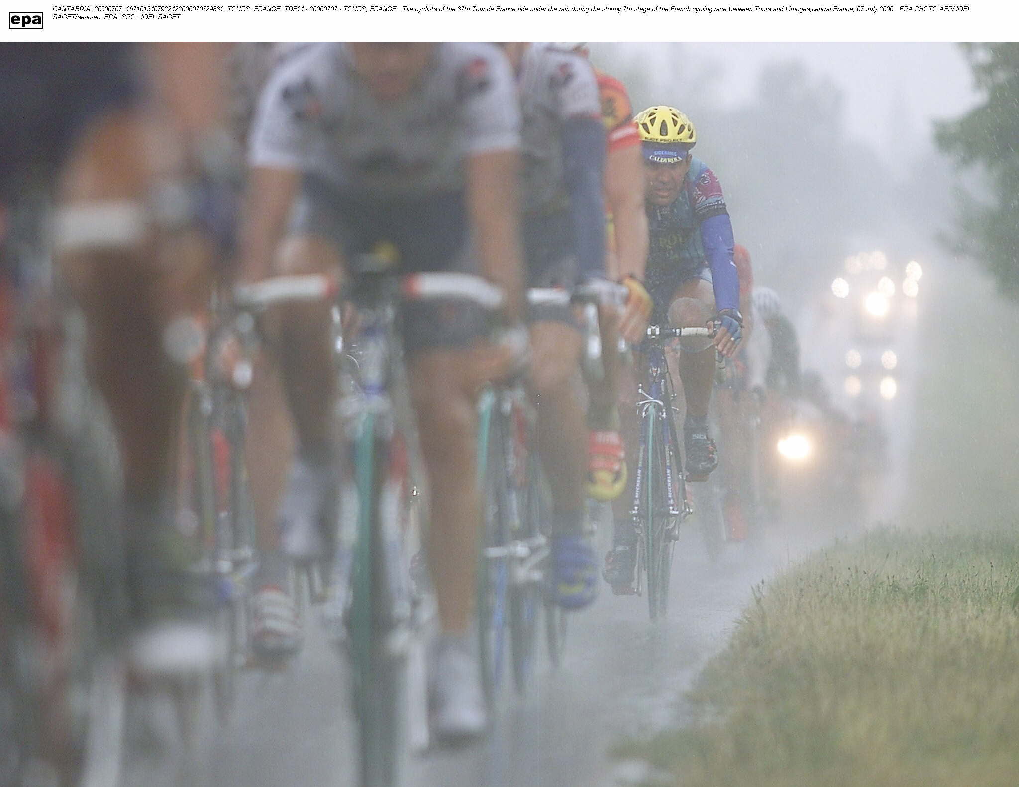 Varios ciclistas pedalean bajo la lluvia.