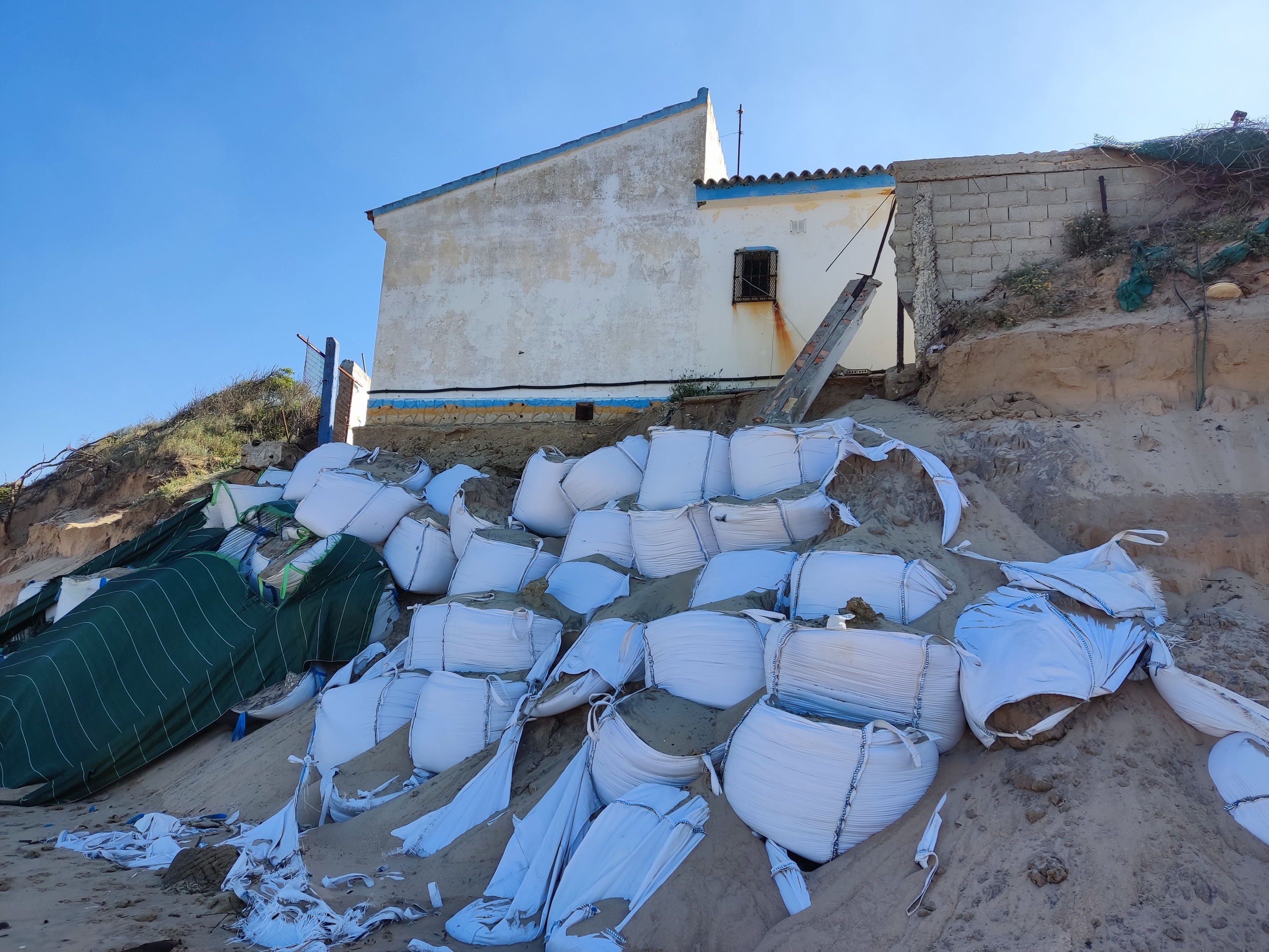 La casa de Punta Candor protegida con sacos terreros antes de ser demolida y cuando ya había perdido la terraza que la rodeaba.