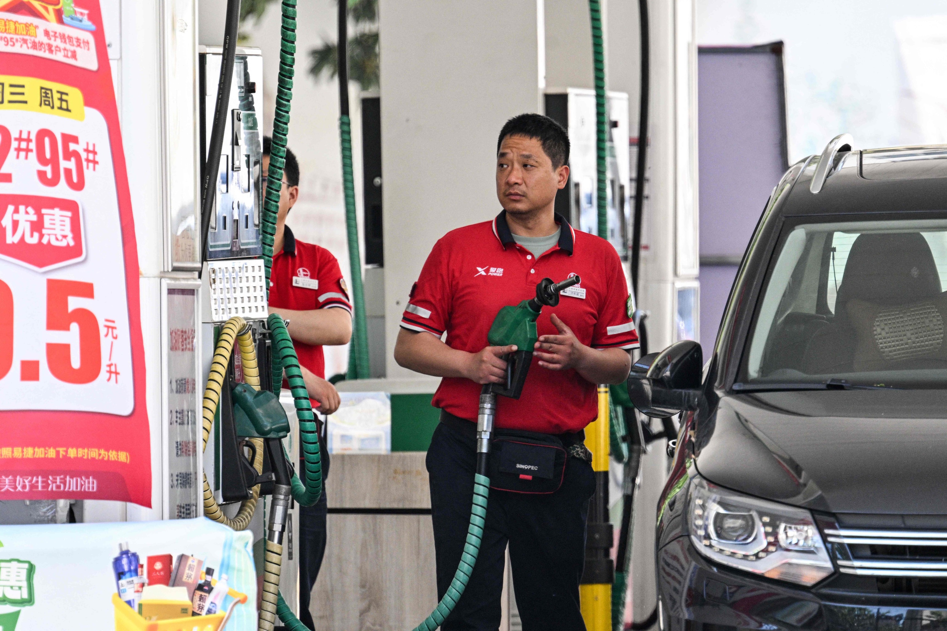 Un empleado llena el depósito de un coche en una gasolinera de Shanghái.