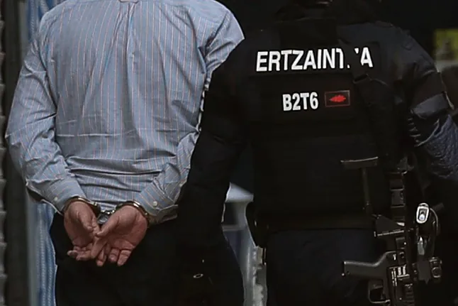 Un ertzaintza con un hombre detenido.