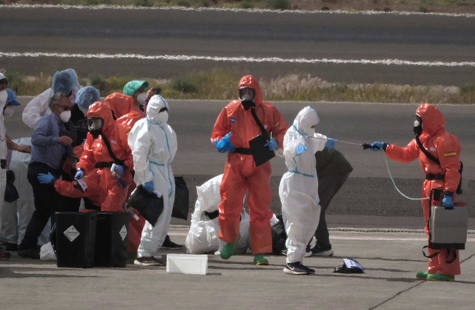 Los pasajeros del crucero son desinfectados a pie de pista antes de embarcar para ser repatriados en el Aeropuerto Sur de Tenerife.