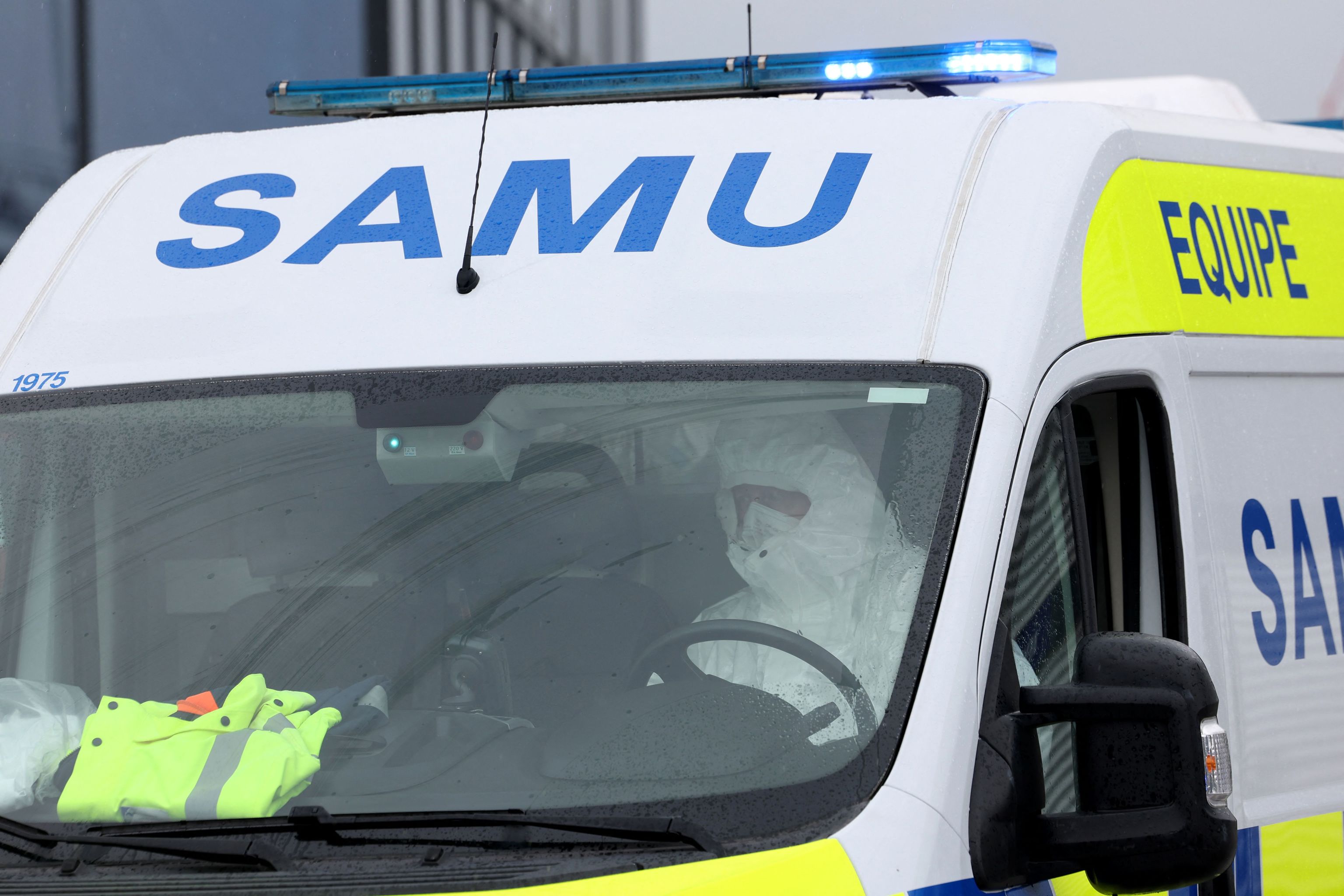 Un hombre con un traje de protecci�n conduce una ambulancia, saliendo de Le Bourget.