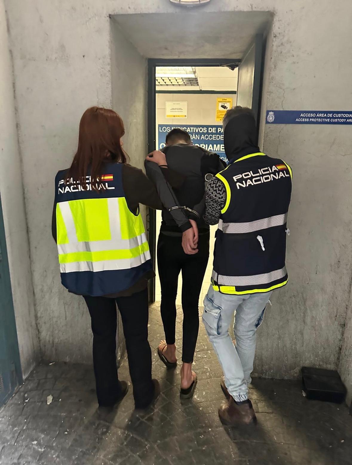 Dos polic�as nacionales custodian a uno de los detenidos.