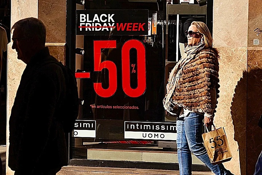 Una mujer pasea ante un cartel con descuentos por el Black Friday en M�laga.