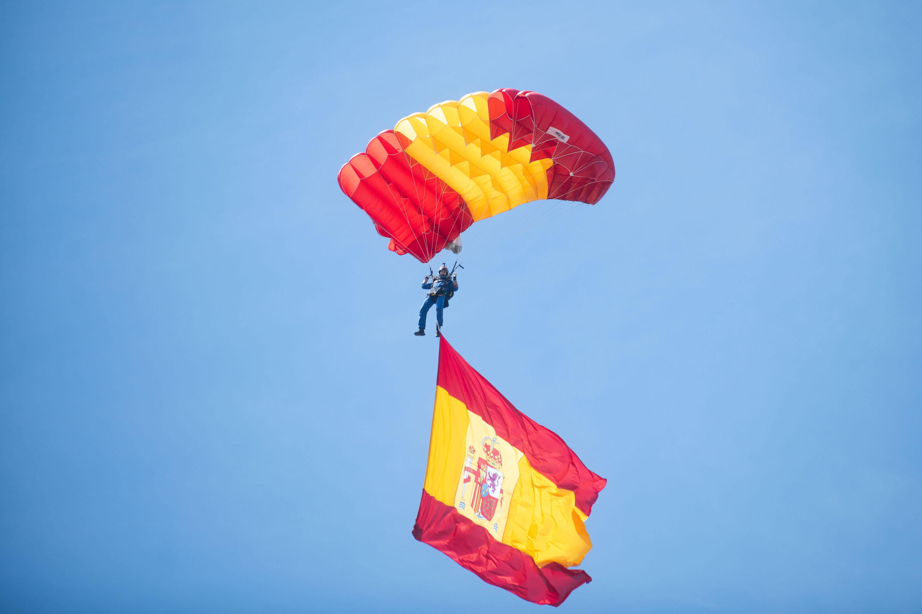 Un paracaidista desciende con la bandera de España durante los actos del Día de las Fuerzas Armadas.