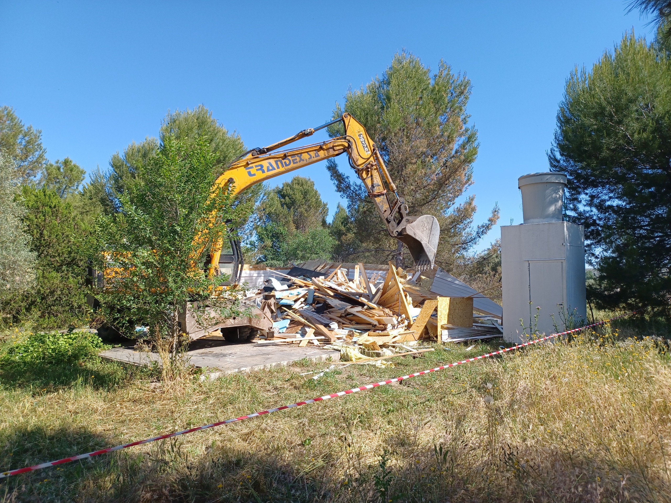 Una excavadora tirando abajo una construcción ilegal.