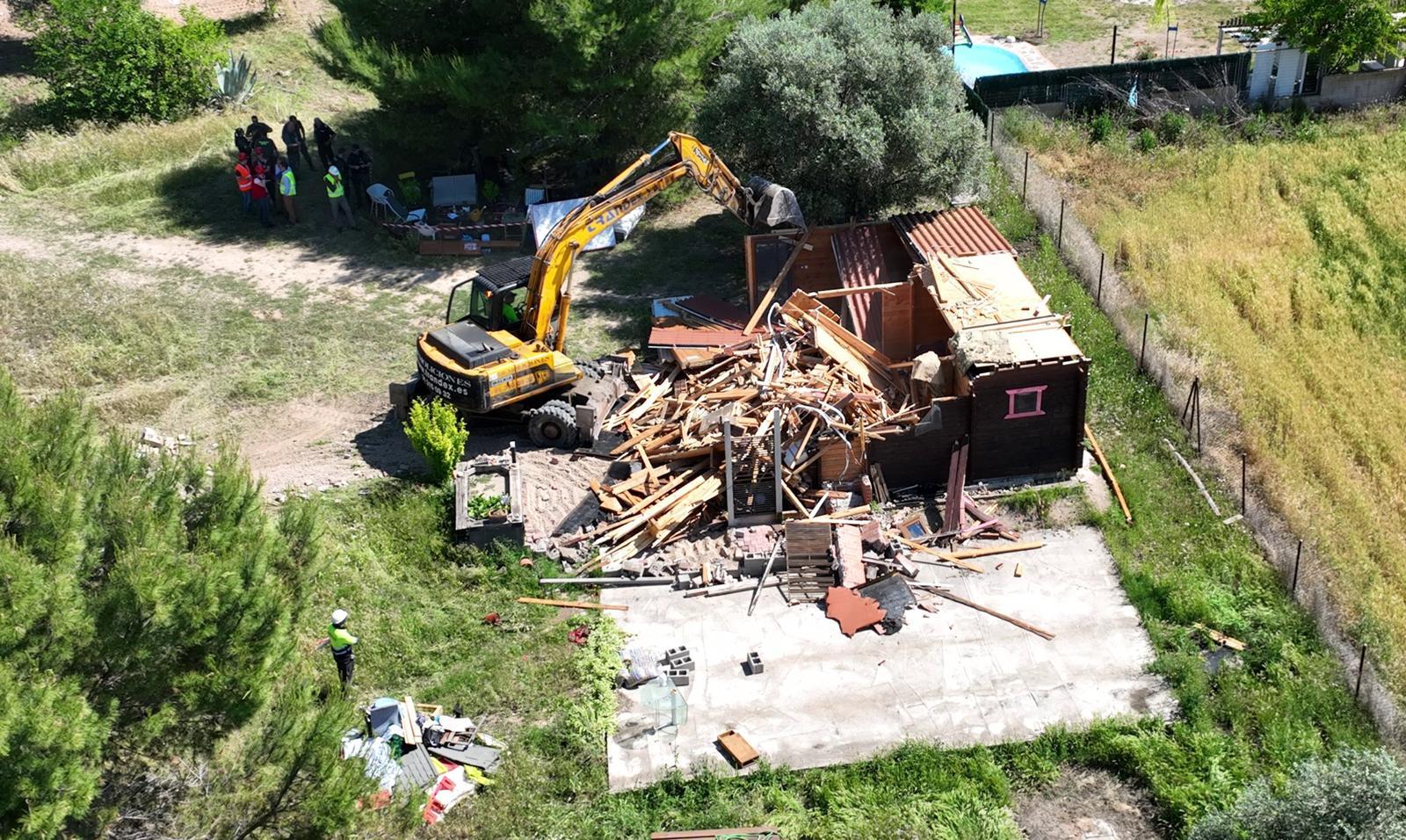 Una excavadora tirando abajo una construcción ilegal.