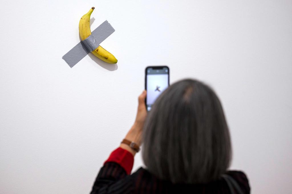 Una visitante fotograf�a la obra "Comedian" durante la presentaci�n de la exposici�n "Dimanche sans fin