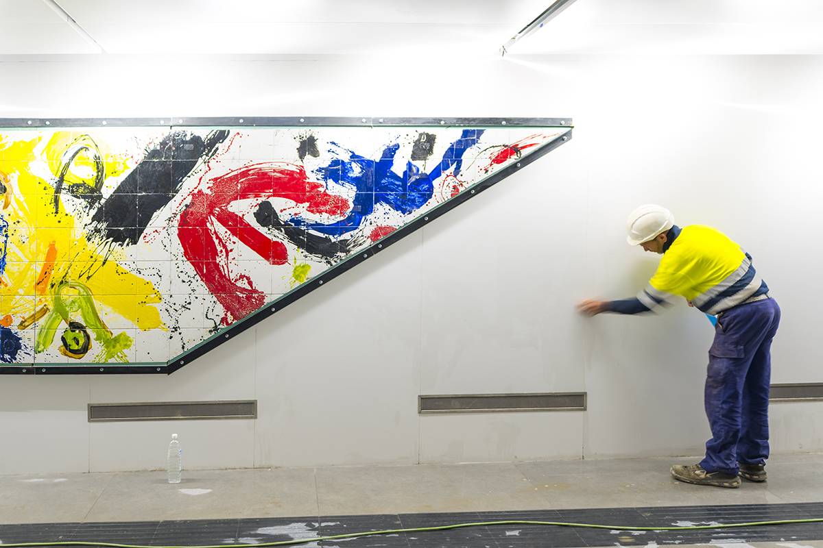 Un operario da los últimos retoques a la colocación de otro de los murales.