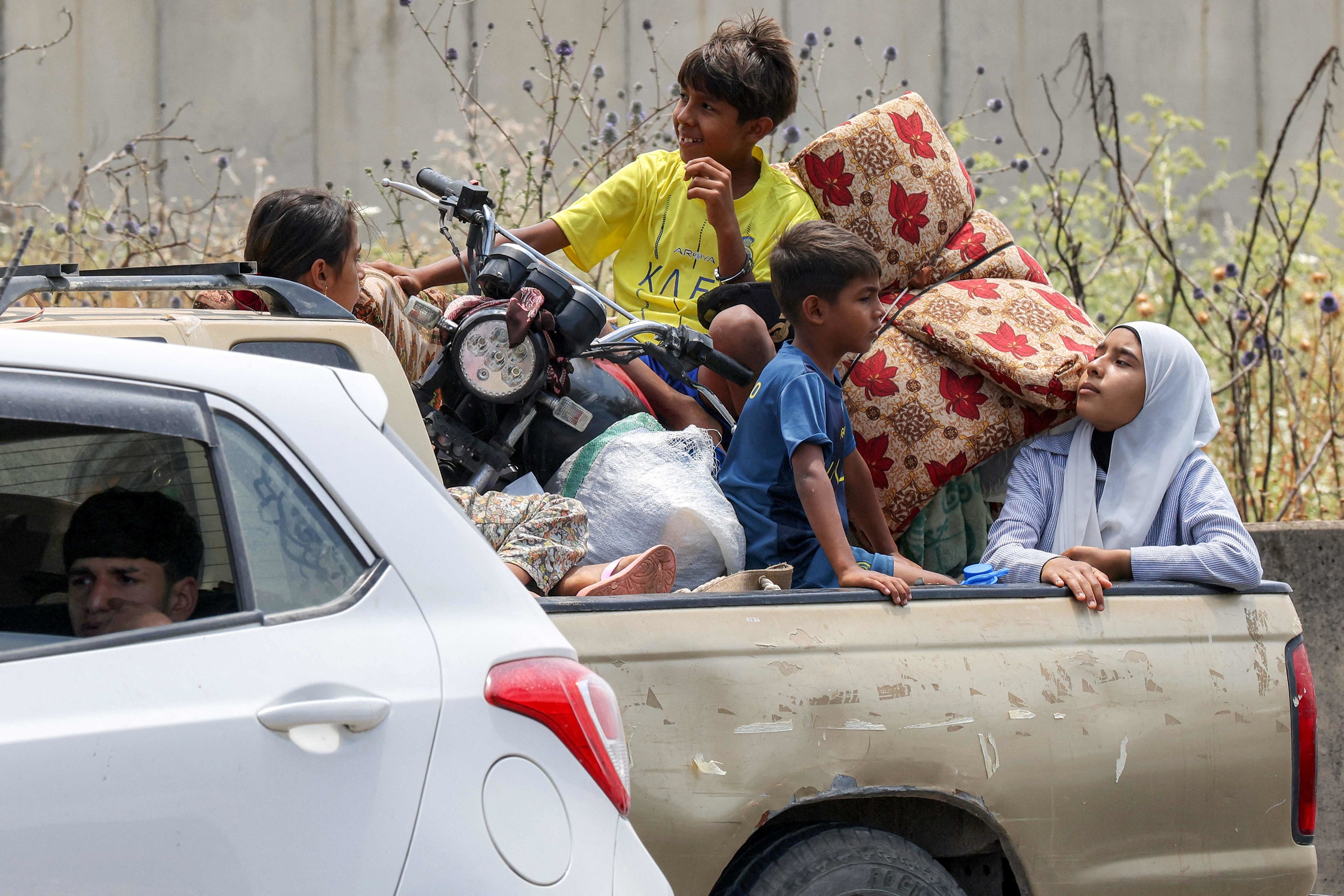 Unos niños sentados en la caja de una camioneta esperan en un atasco, mientras la gente que huye de Tiro, en el sur del Líbano, tras la advertencia de evacuación de Israel.