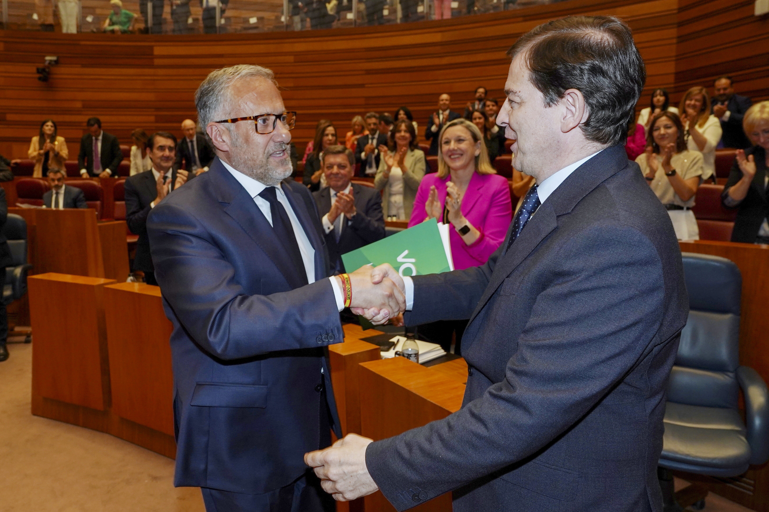 El presidente Alfonso Fernández Mañueco recibe la felicitación de Carlos Pollán (Vox) tras el debate de investidura