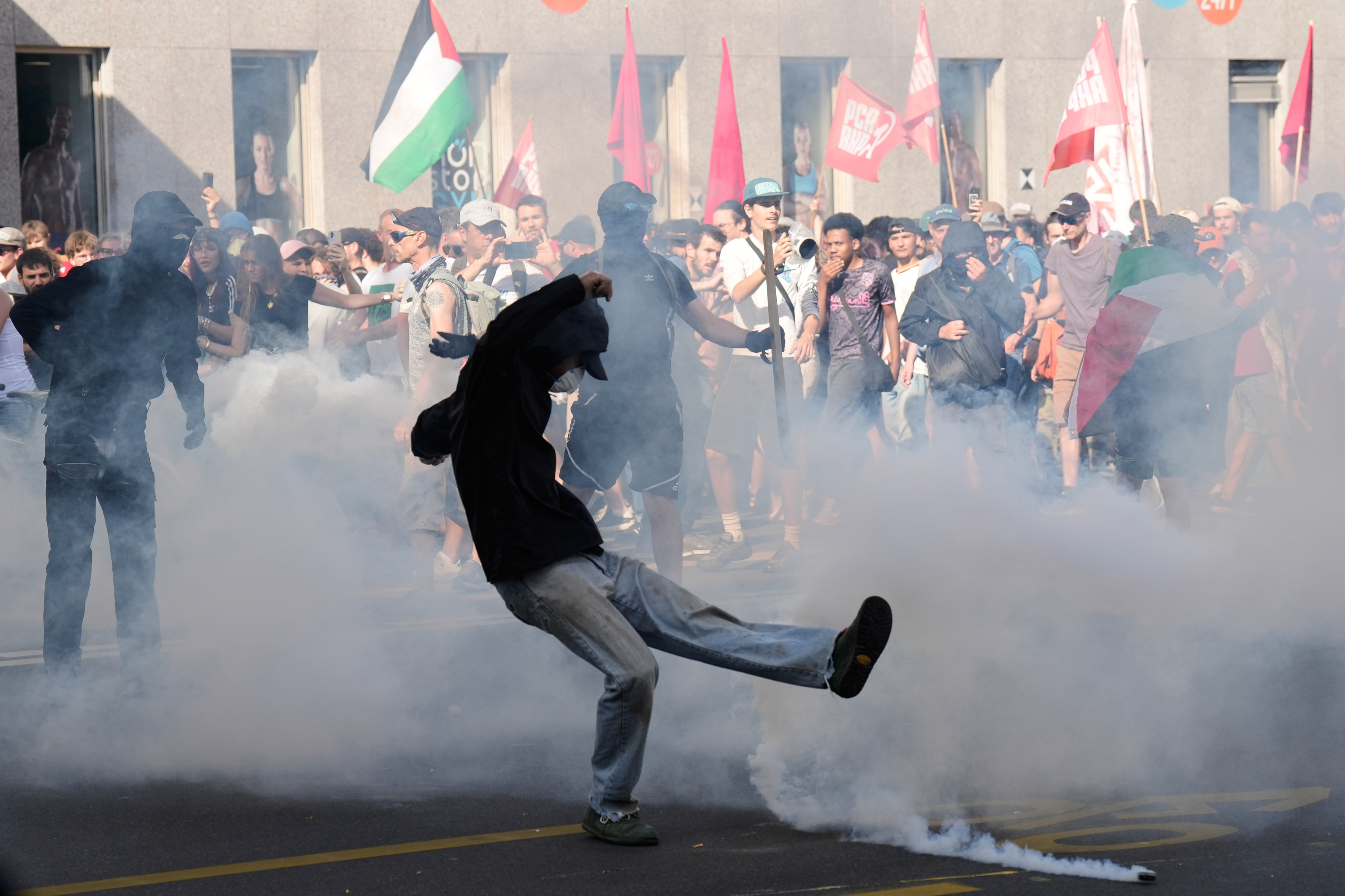Un manifestante patea un bote de gas lacrimógeno lanzado por la Policía.