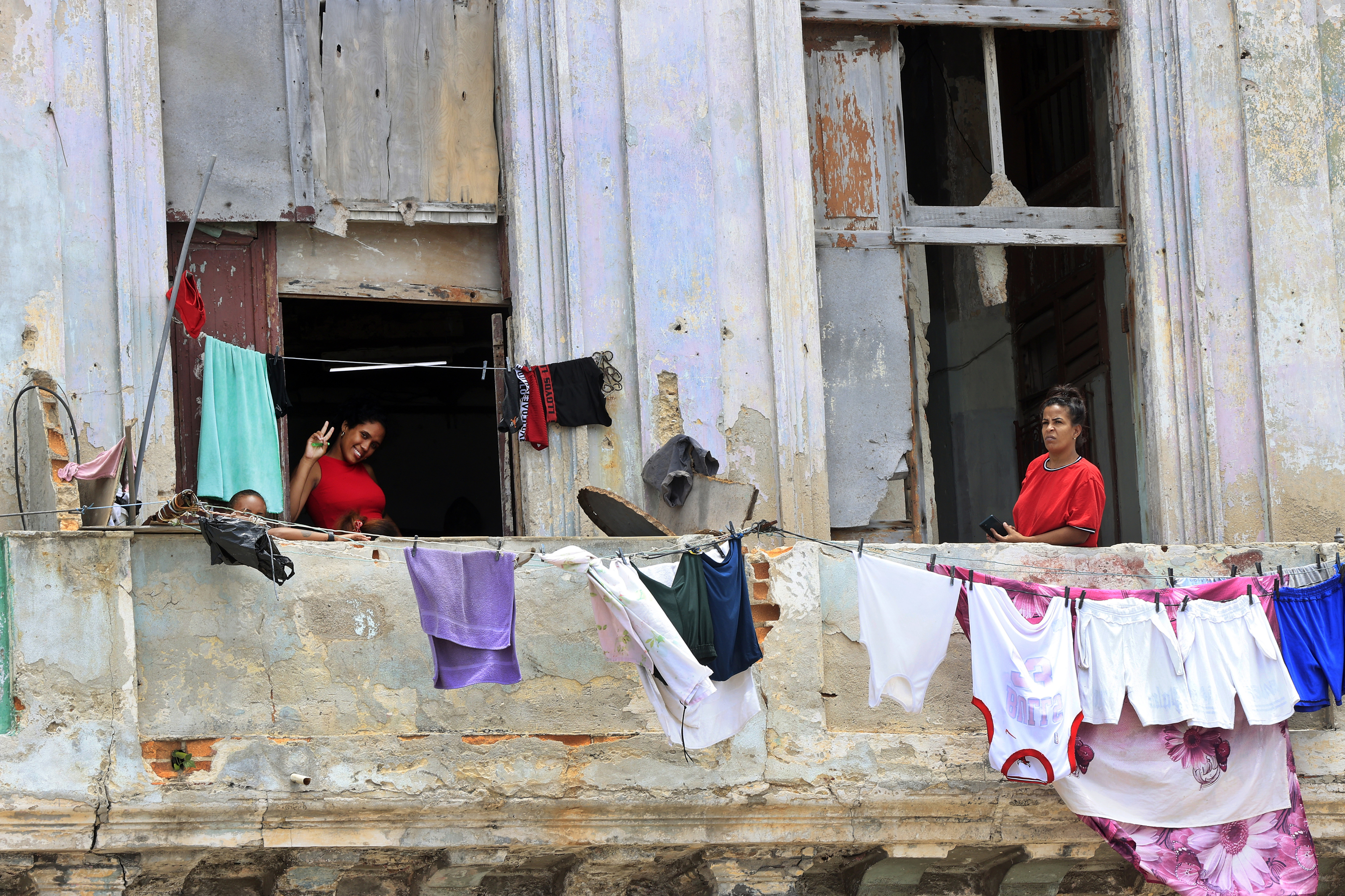 Dos mujeres saludan desde el balcón de una casa en La Habana.