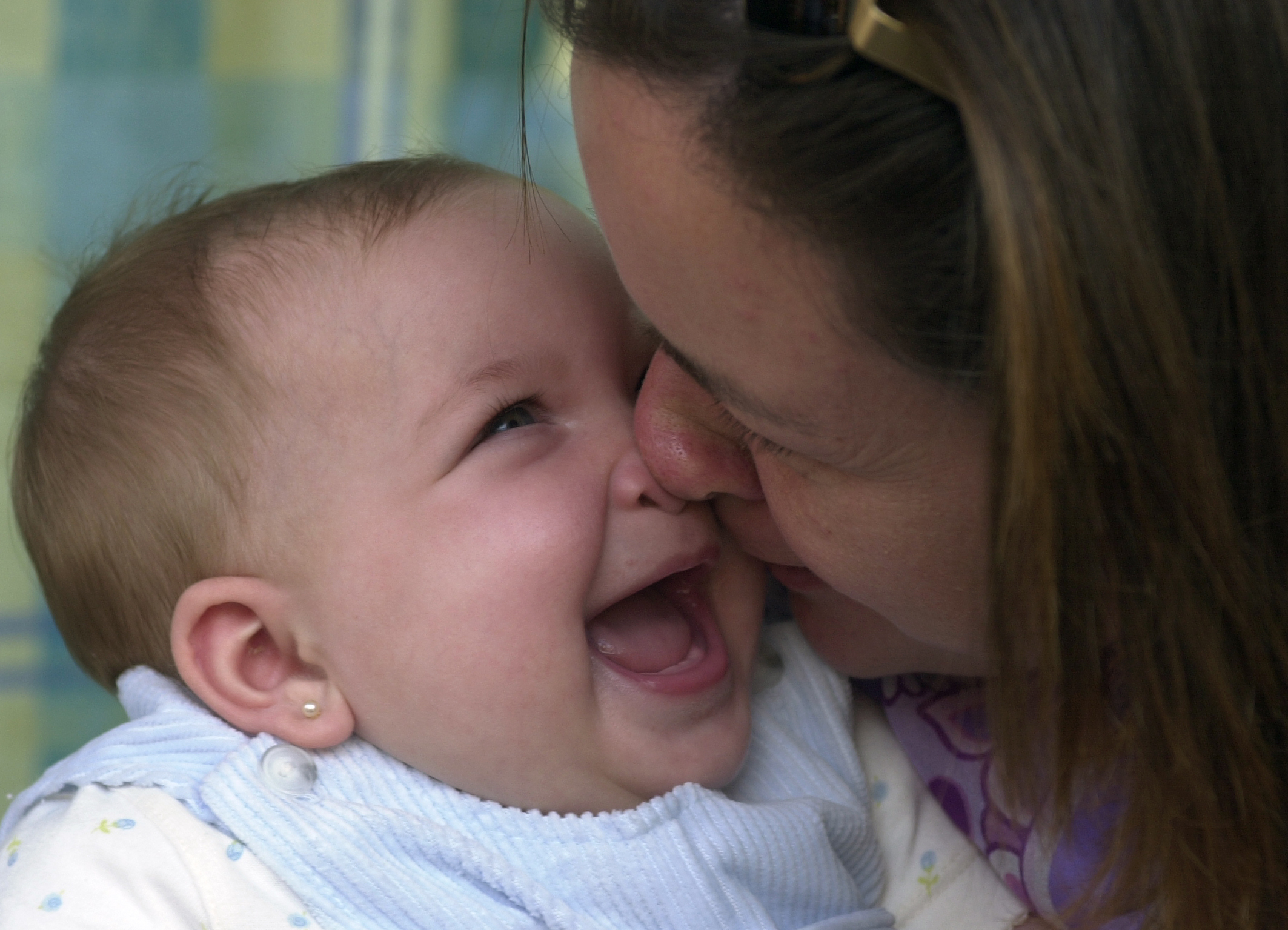 Un bebé de pocos meses sonríe ante los arrumacos de su madre.