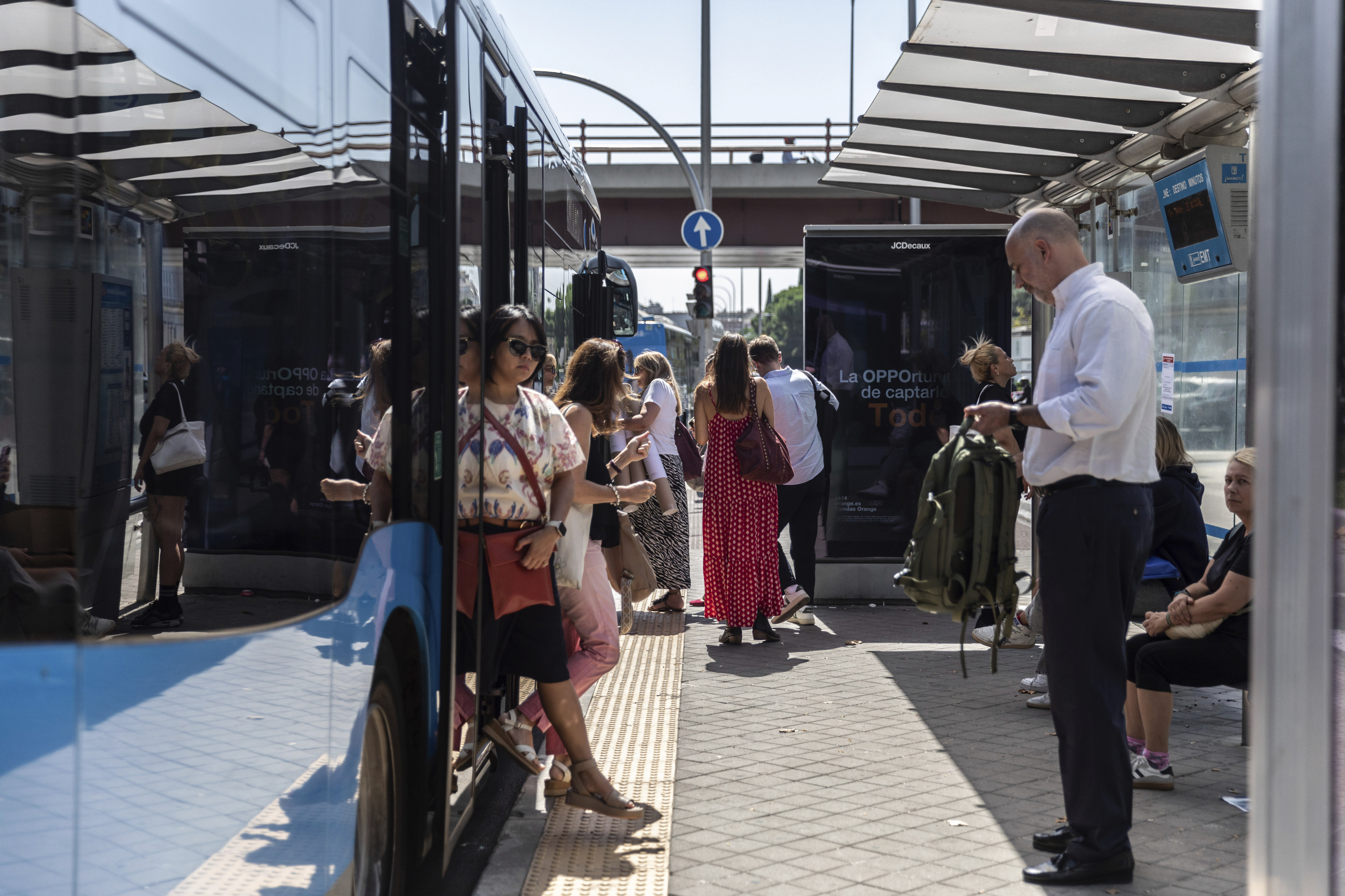 Varios viajeros en una parada de autobús de Nuevos Ministerios.