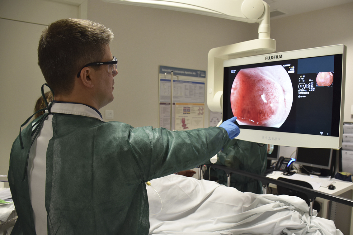 Un profesional sanitario mira un monitor mientras realiza una colonoscopia.