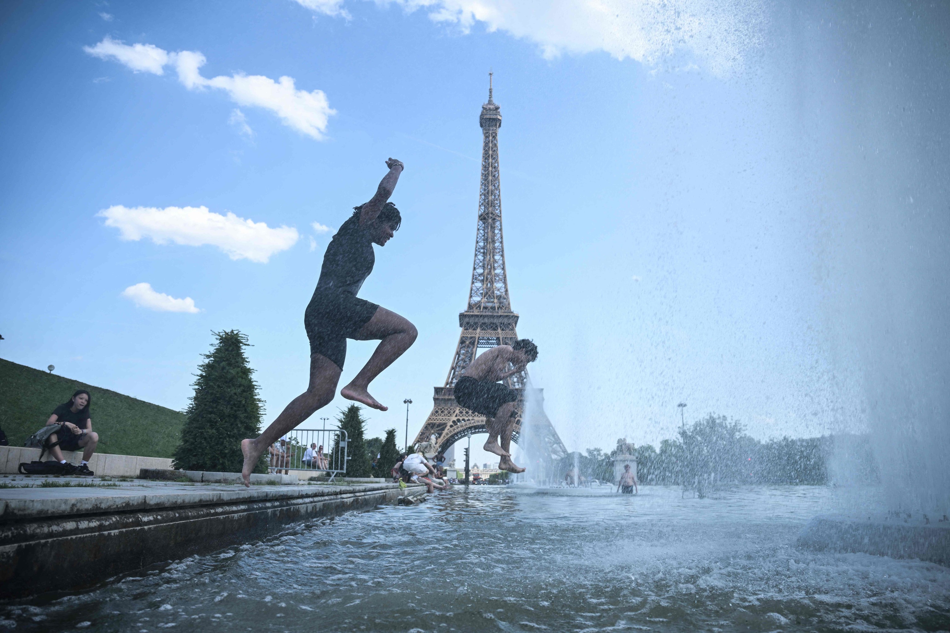 Dos jóvenes saltan a la Fuente del Trocadero o de Varsovia, con la Torre Eiffel al fondo