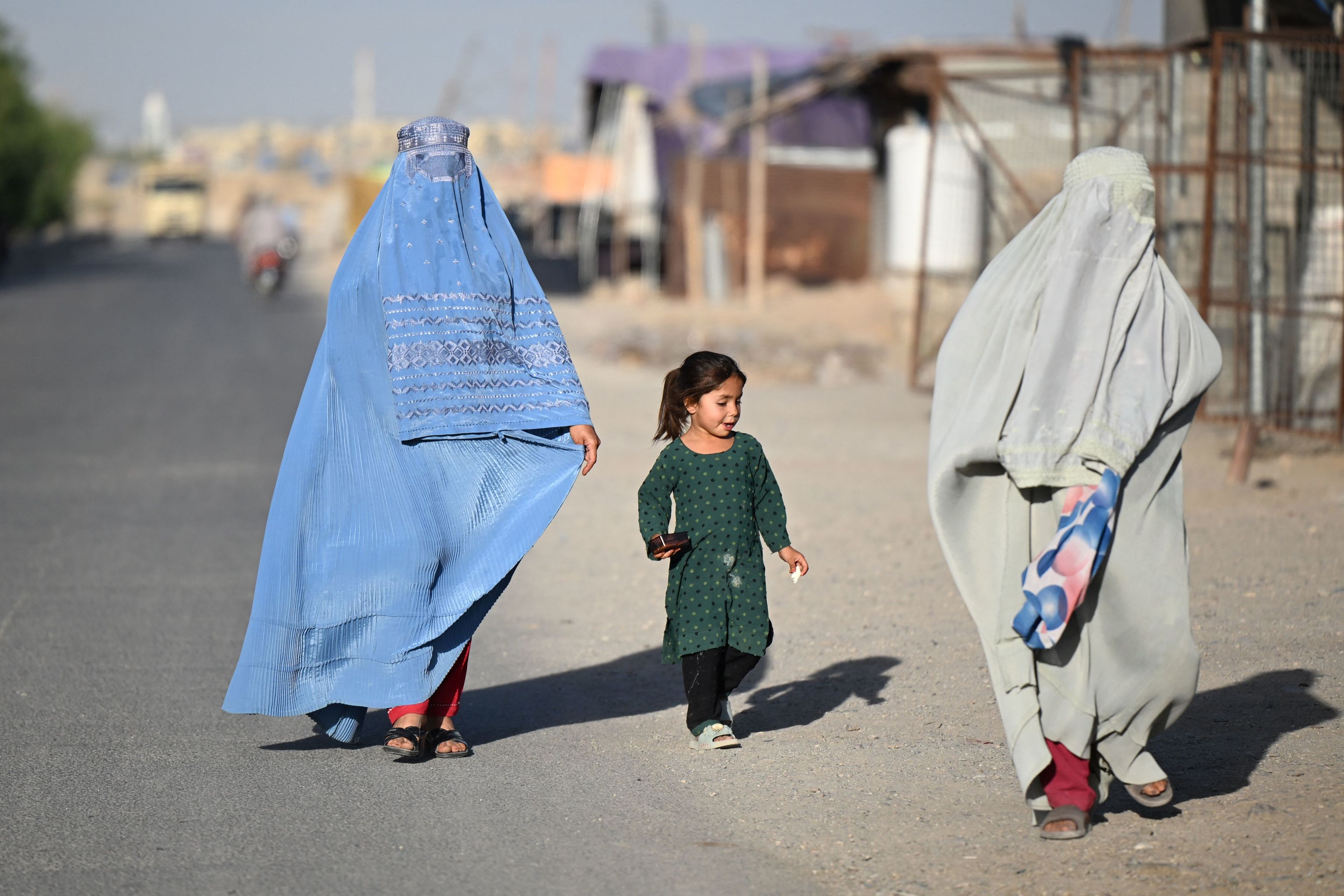 Unas mujeres afganas ataviadas con burka, acompañadas de una niña, caminan el pasado domingo por una calle de la localidad de Loy Viala, en Kandahar (Afganistán).