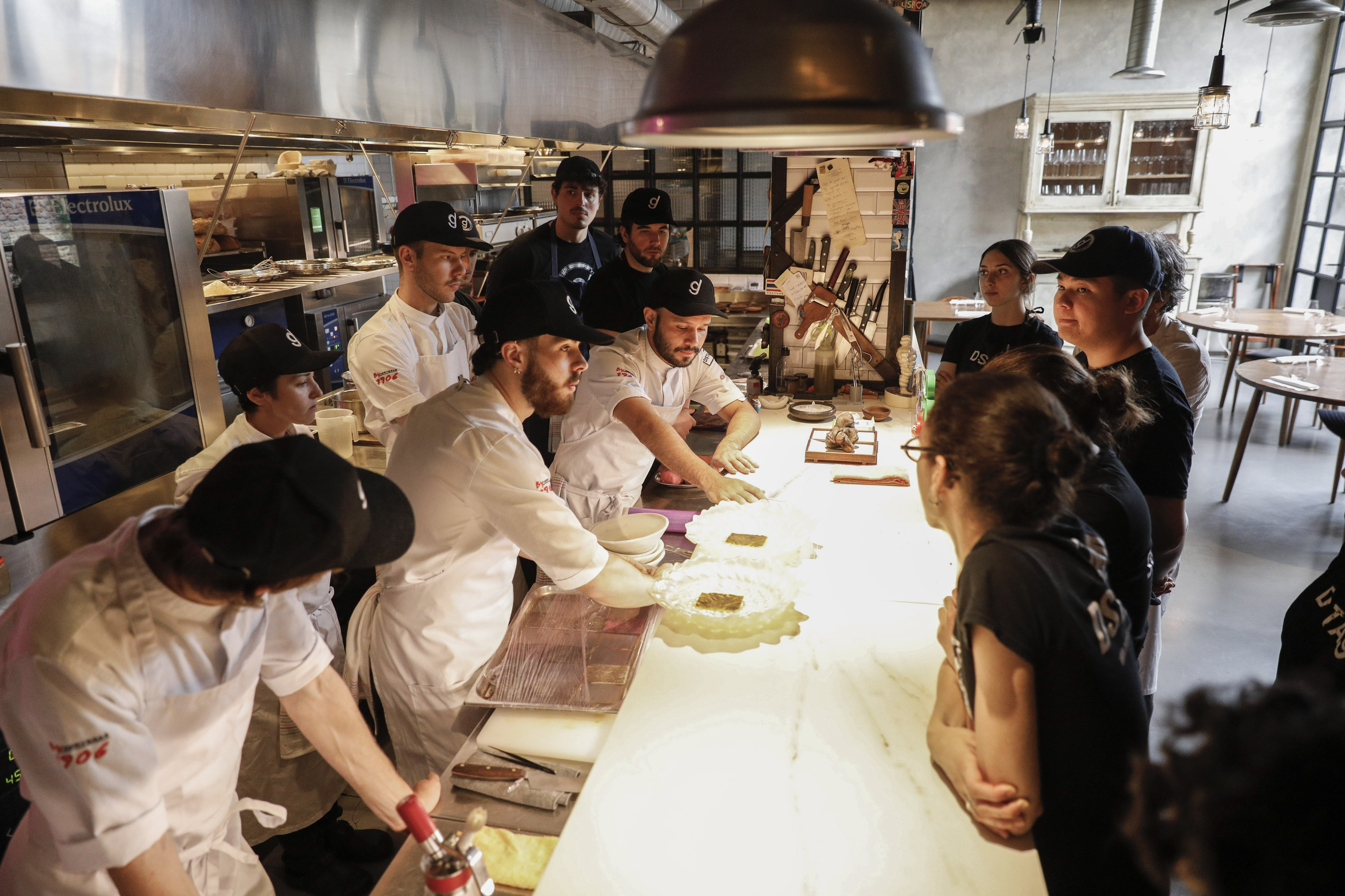 El equipo, atento a las indicaciones de los jefes de cocina antes del servicio.