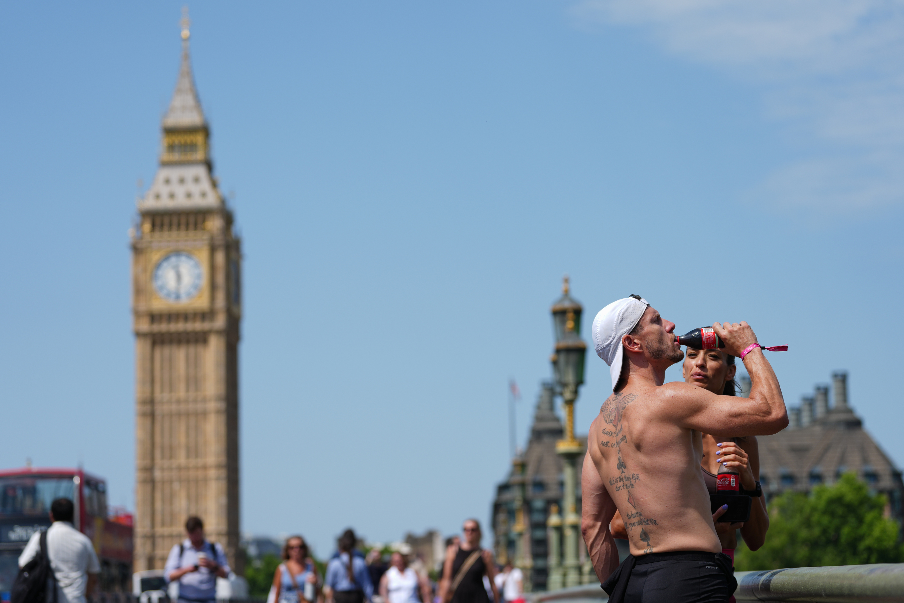 Un hombre bebe sobre el puente de Westminster.
