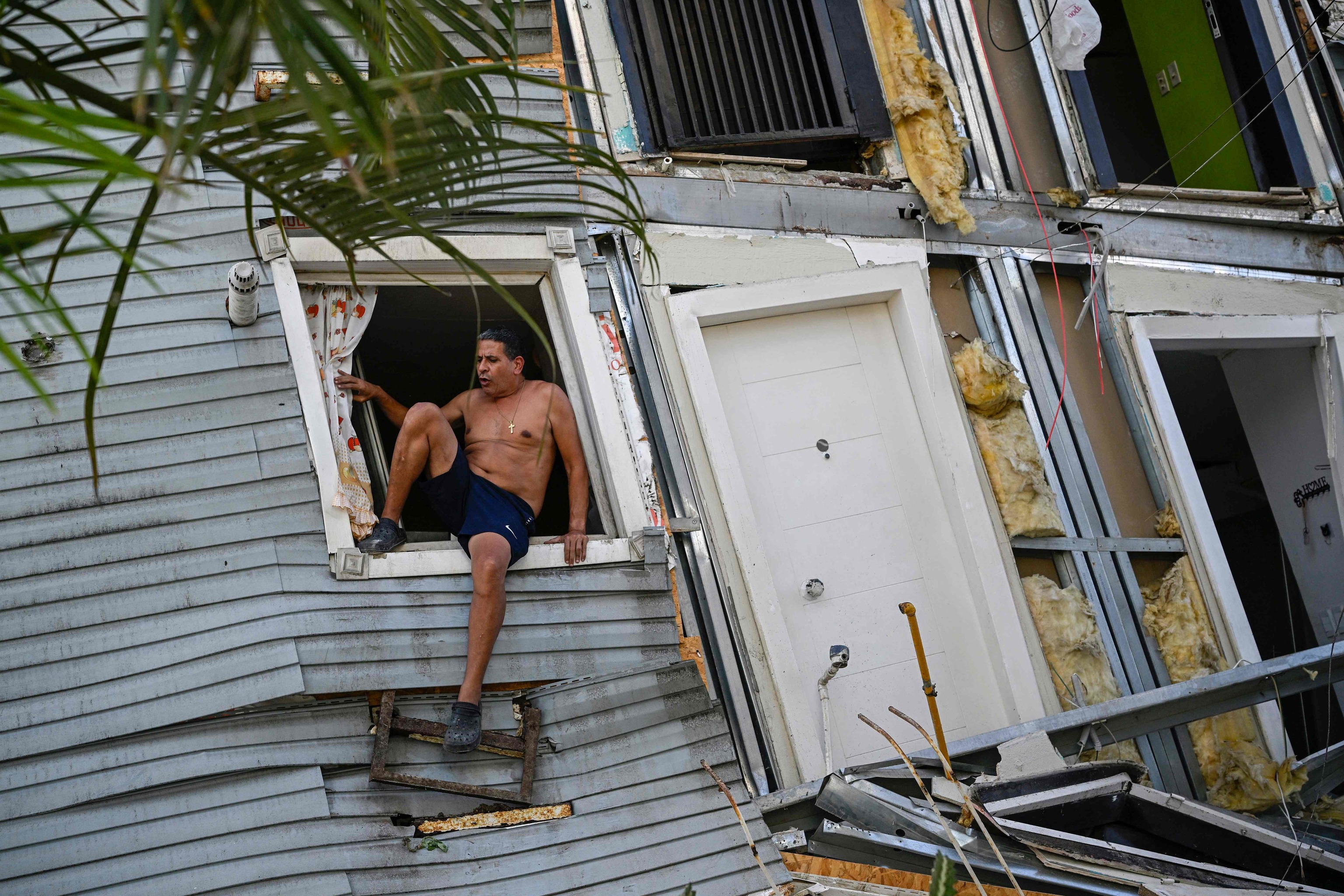 Un hombre trepa por la ventana de un edificio dañado en Catia La Mar, este jueves, tras el doblete sísmico en Venezuela.