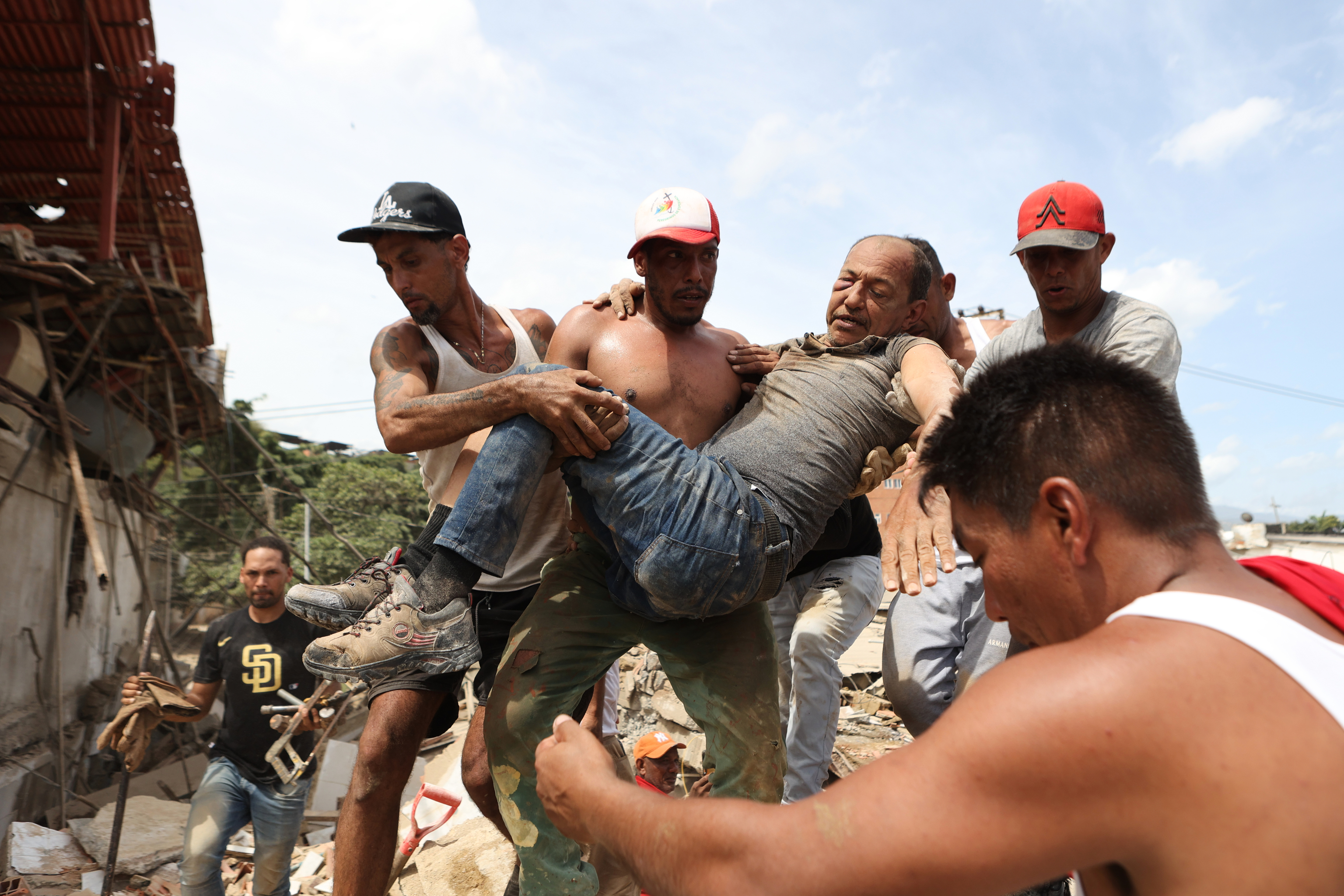 Varios vecinos trasladan a un hombre rescatado de entre los escombros de un edificio derrumbado en la Guaira, Venezuela.