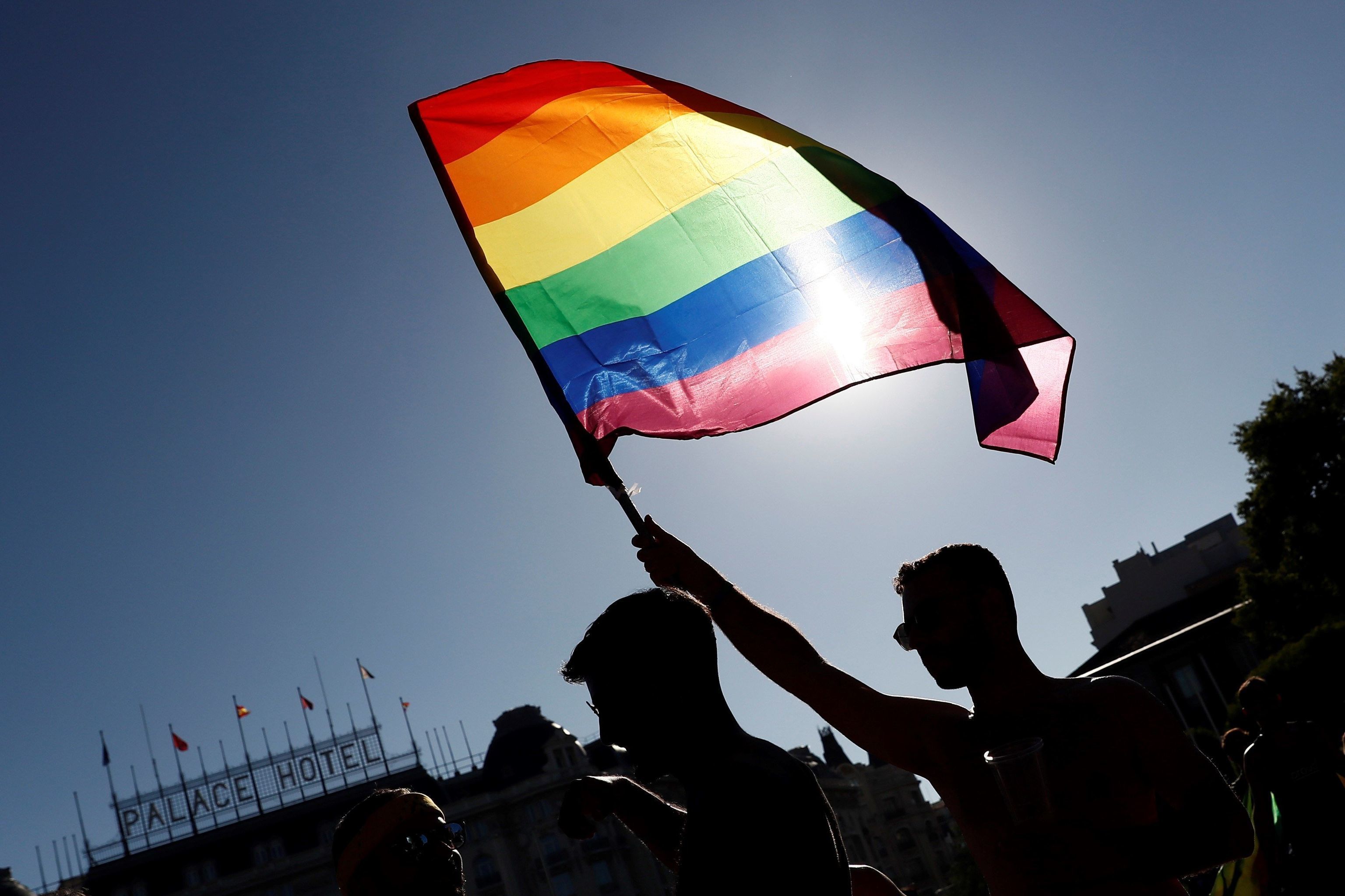 Un hombre alza una bandera del Orgullo LGTBIQ+.