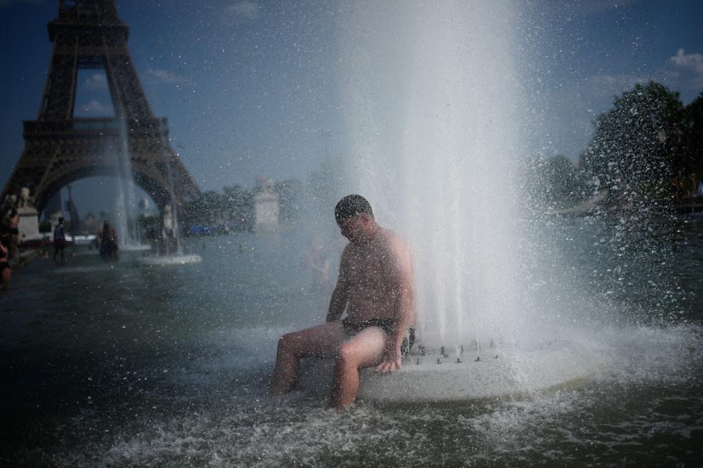 Una persona se refresca en una fuente en el Trocadero, cerca de la Torre Eiffel, durante la ola de calor que azota Francia.
