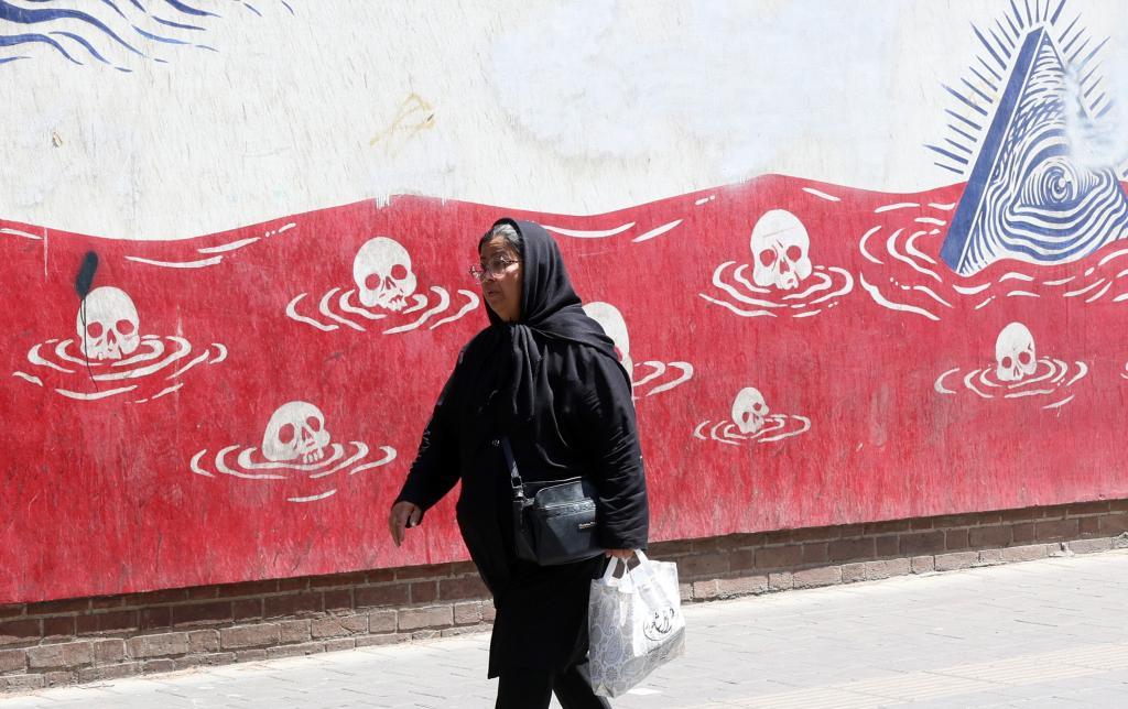 Una mujer iraní camina frente a un mural antiestadounidense junto a la antigua embajada de EEUU en Teherán.